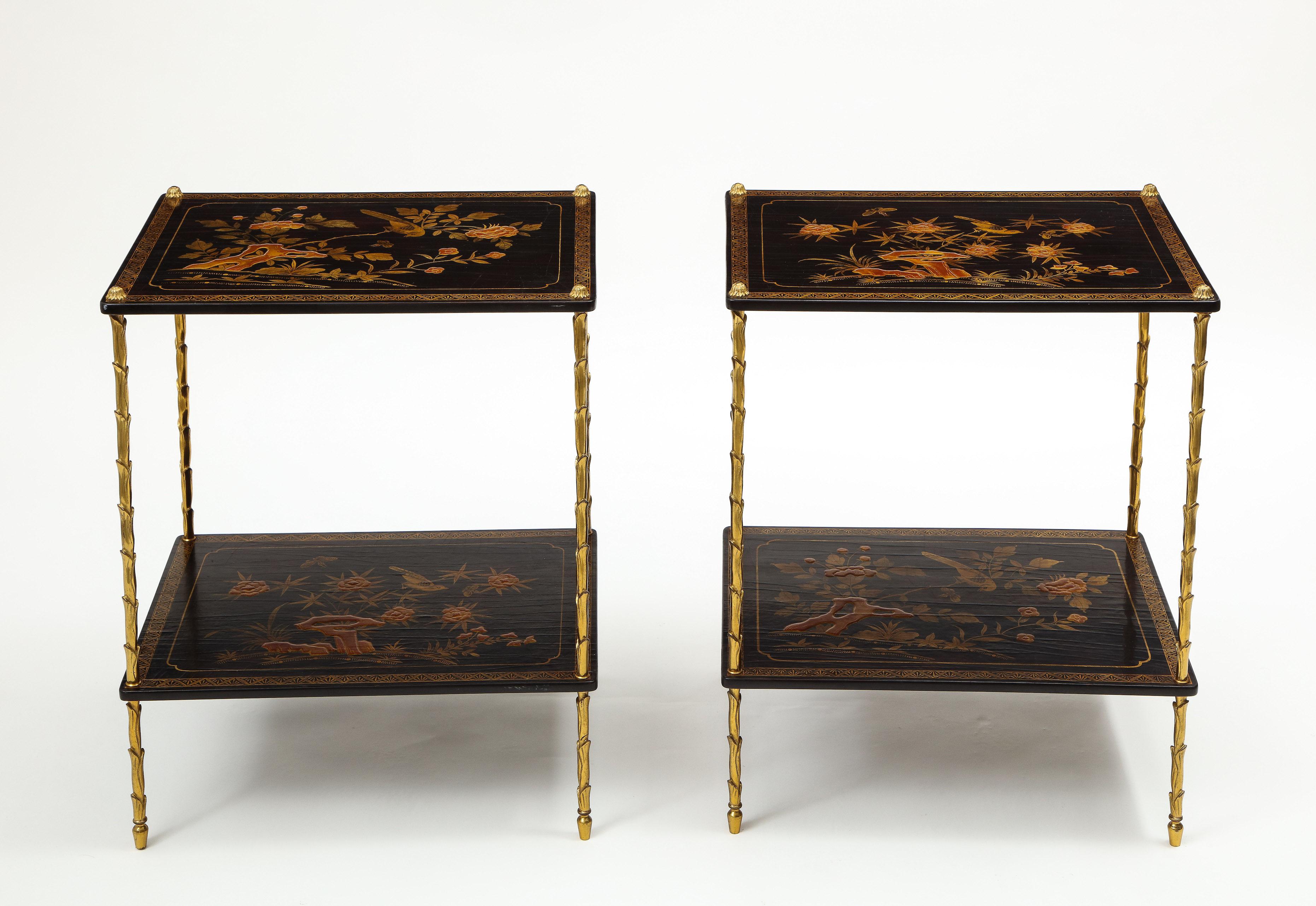Each with two black rectangular shelves decorated with flowering tree peonies and birds and butterflies and a broad zig zag border; supported on gilt-metal palm tree uprights.