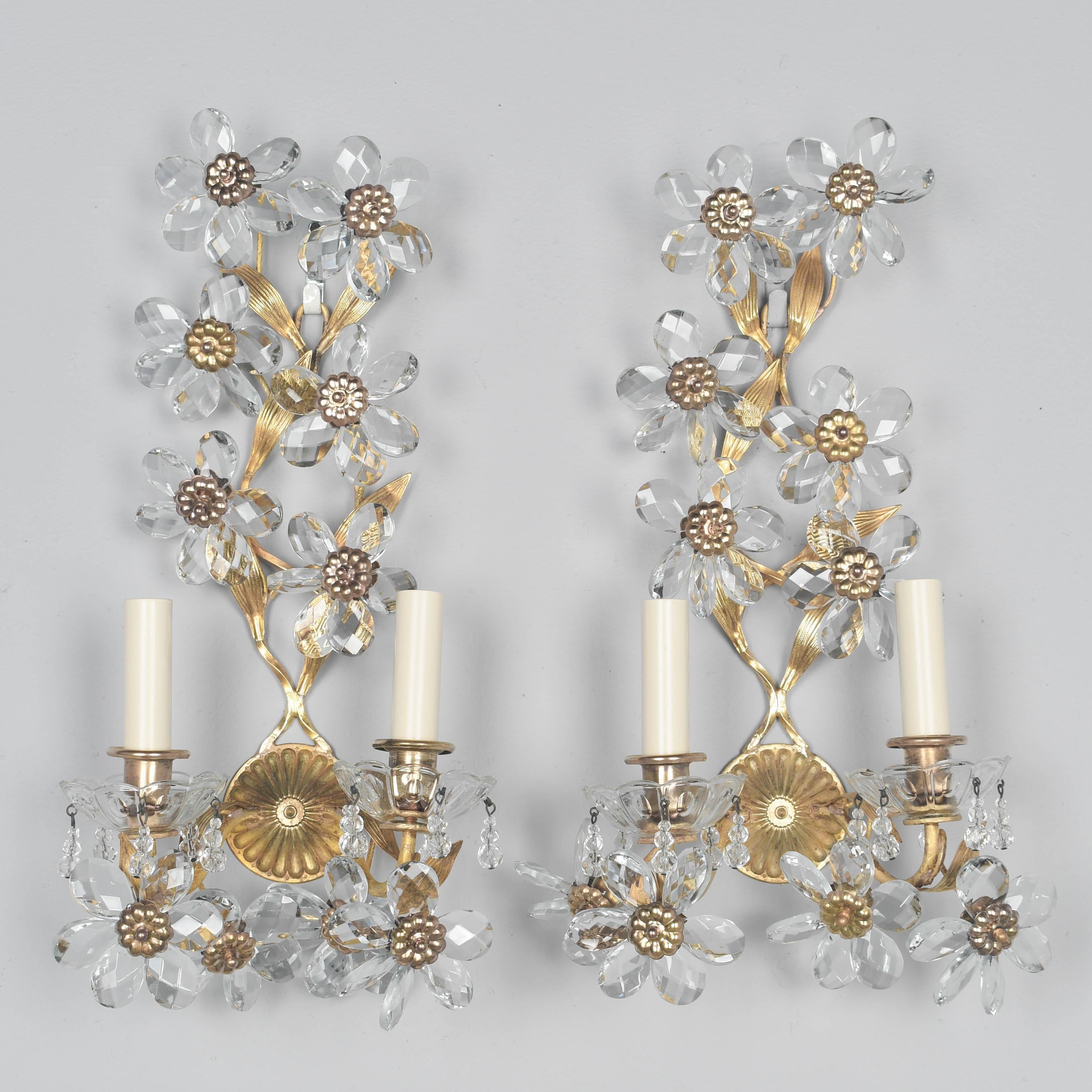 Coppia di appliques francesi Art Déco in ottone fuso e cristallo della Maison Baguès. Una fusione pesante di buona qualità con forme a foglia, ciascuna con dieci fiori di cristallo sfaccettato con rosette in ottone stampate. Due bracci di candela