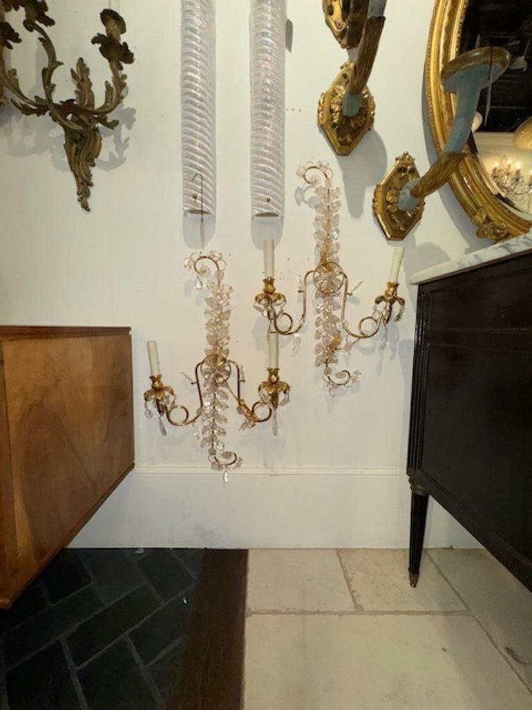 Questo annuncio presenta una coppia di eleganti appliques ispirate al design della Maison Bagues. Le applique sono impreziosite da squisiti elementi in cristallo di rocca e ottone, che creano un look lussuoso e sofisticato. Ogni applique è dotata di