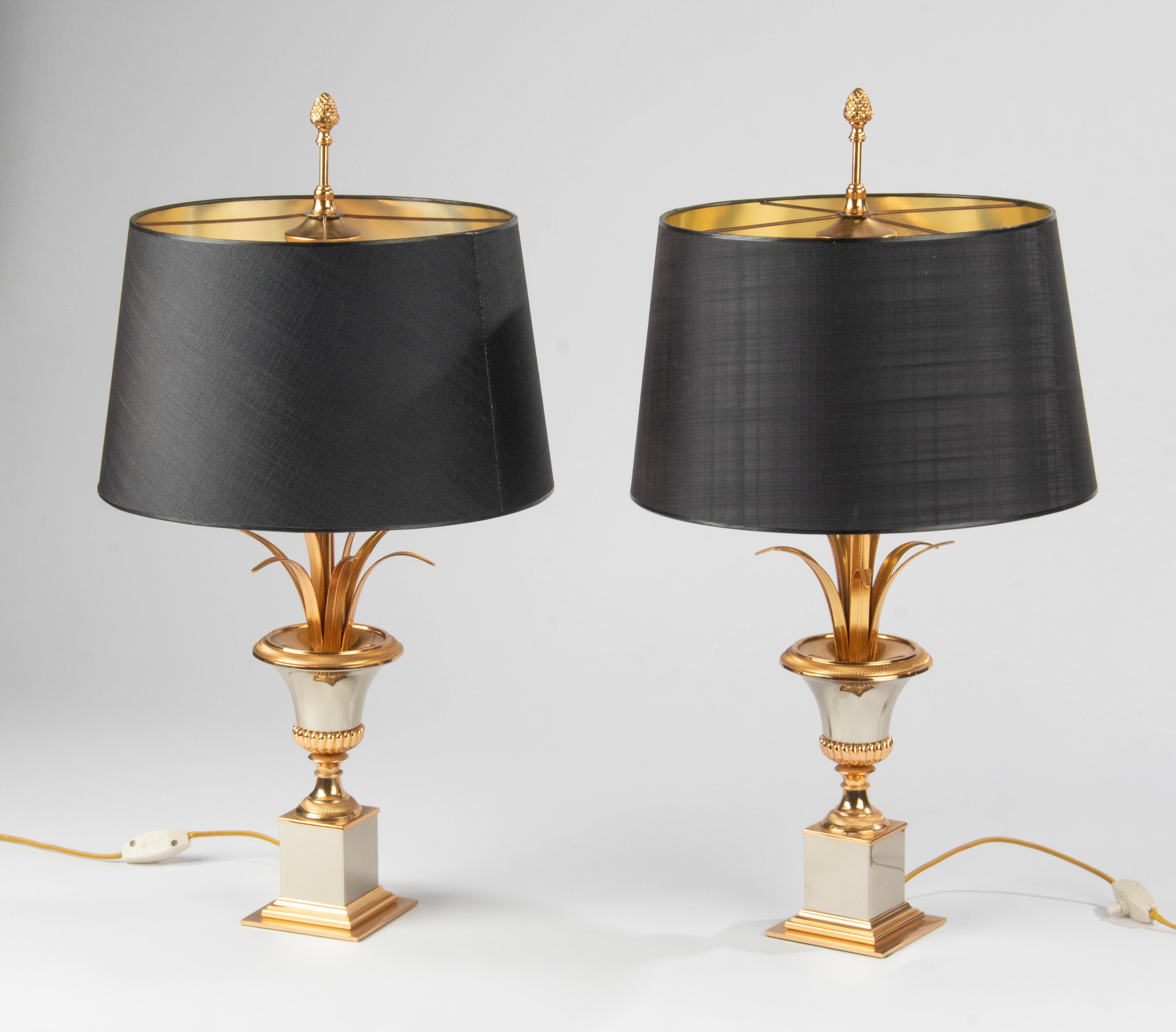A matching pair of chic and iconic table lamps in the style of Maison Charles, Paris. The name of the lamp is Vase Roseaux. The lamp is made of polished chrome plated metal and brass colored metal. With reed or palm leaves in a vase. Each lamp has