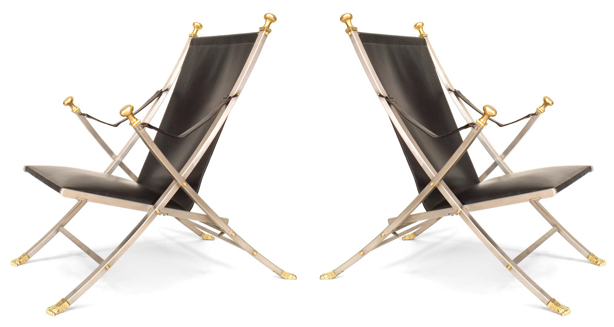 Pair of French Art Moderne (1940/50s) steel campaign Armchairs with brass claw feet and finials on back and arms with black leather seat and back (MAISON JANSEN) (Damaged on one of the straps)
