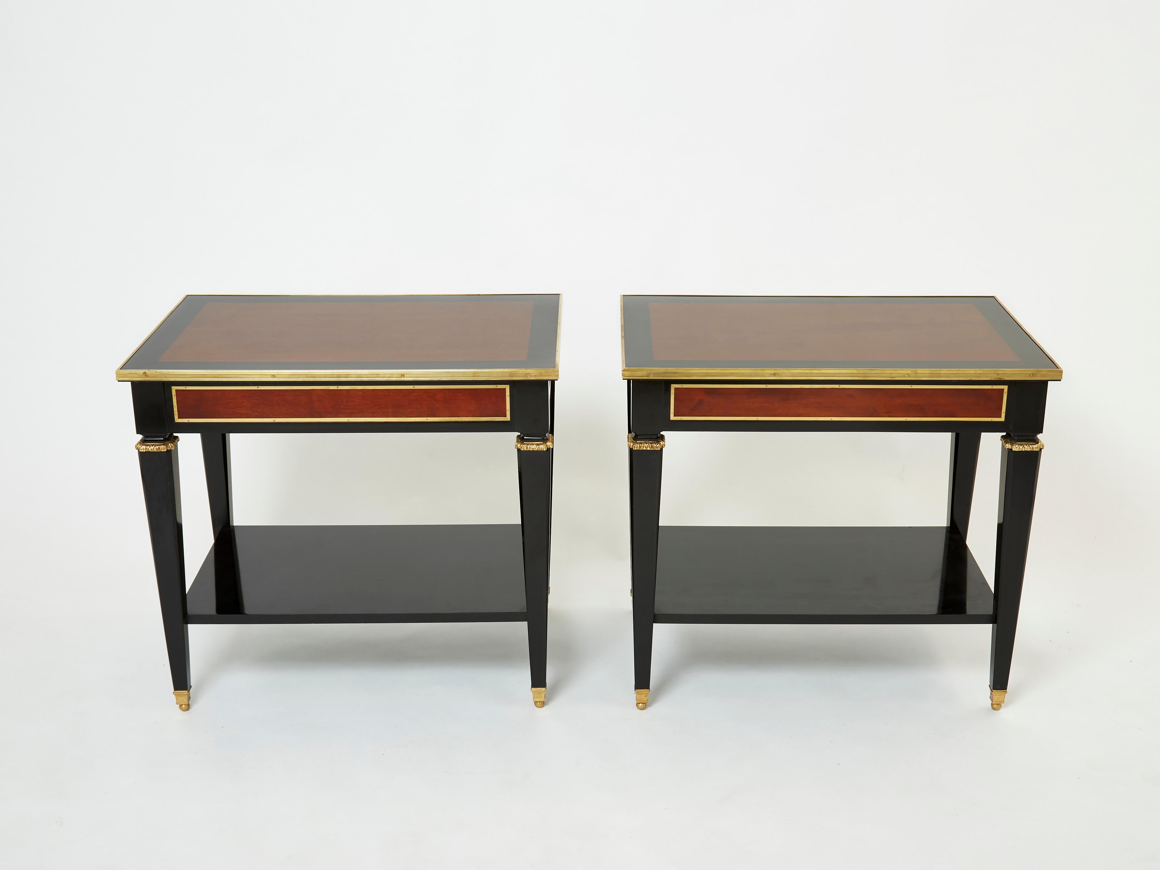 This rare pair of two-tier end tables or side tables by French house Maison Jansen was created in the early 1950s with mahogany and black varnished wood, with brass details and accents. These tables are typical of the timeless French neoclassical