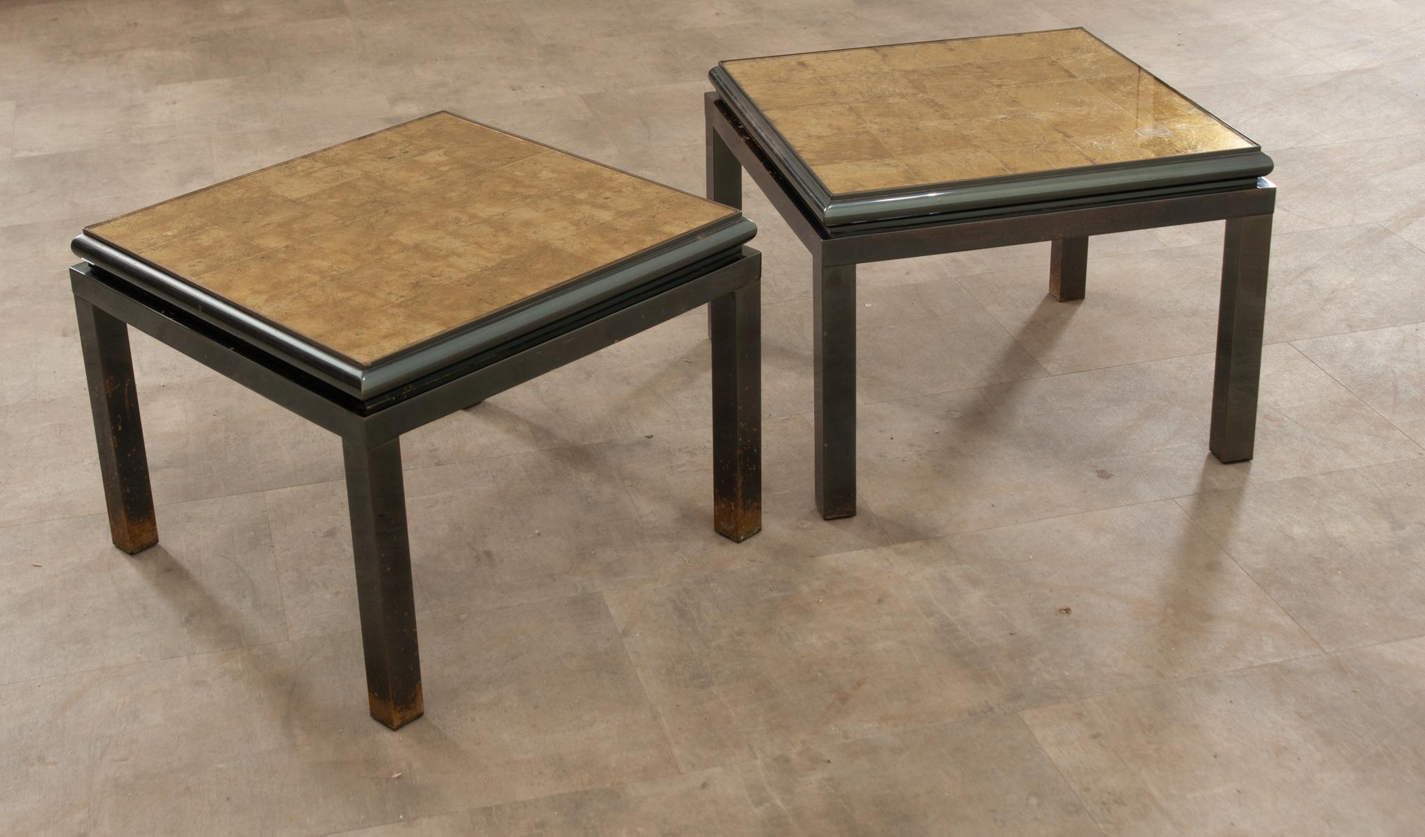 This pair of coffee tables or side tables were designed by Guy Lefevre in the 1970s for internationally renowned furniture maker Maison Jansen. The underside of the glass tops have been hand gilt so that each square of gold is minimally defined and