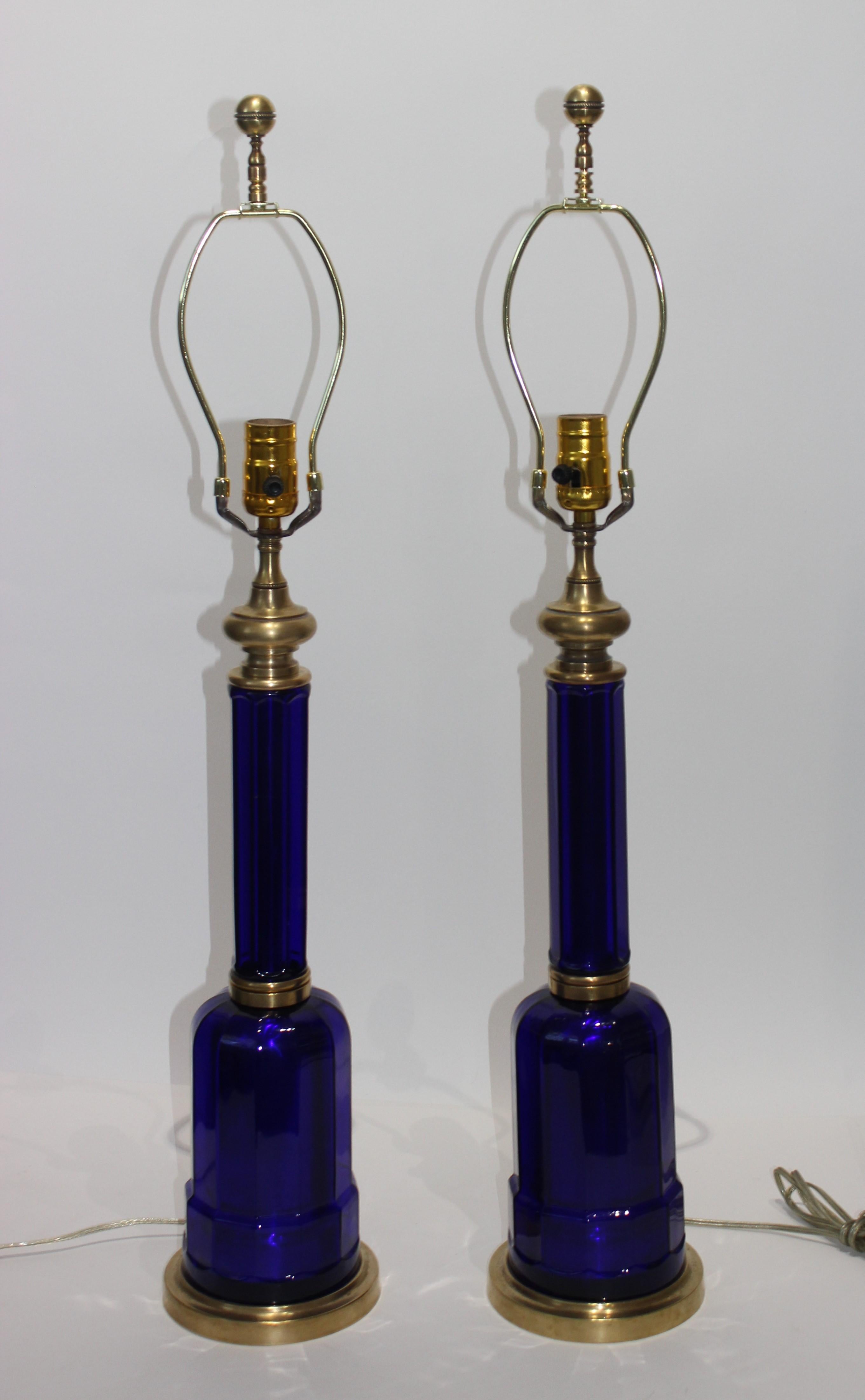 The stylish and chic pair of cobalt blue glass lamps are attributed to Maison Jansen were acquired from a Palm Beach estate. The design is based pieces created in the 19th century for oil burning lamps.

The quality of the glass is exceptional and