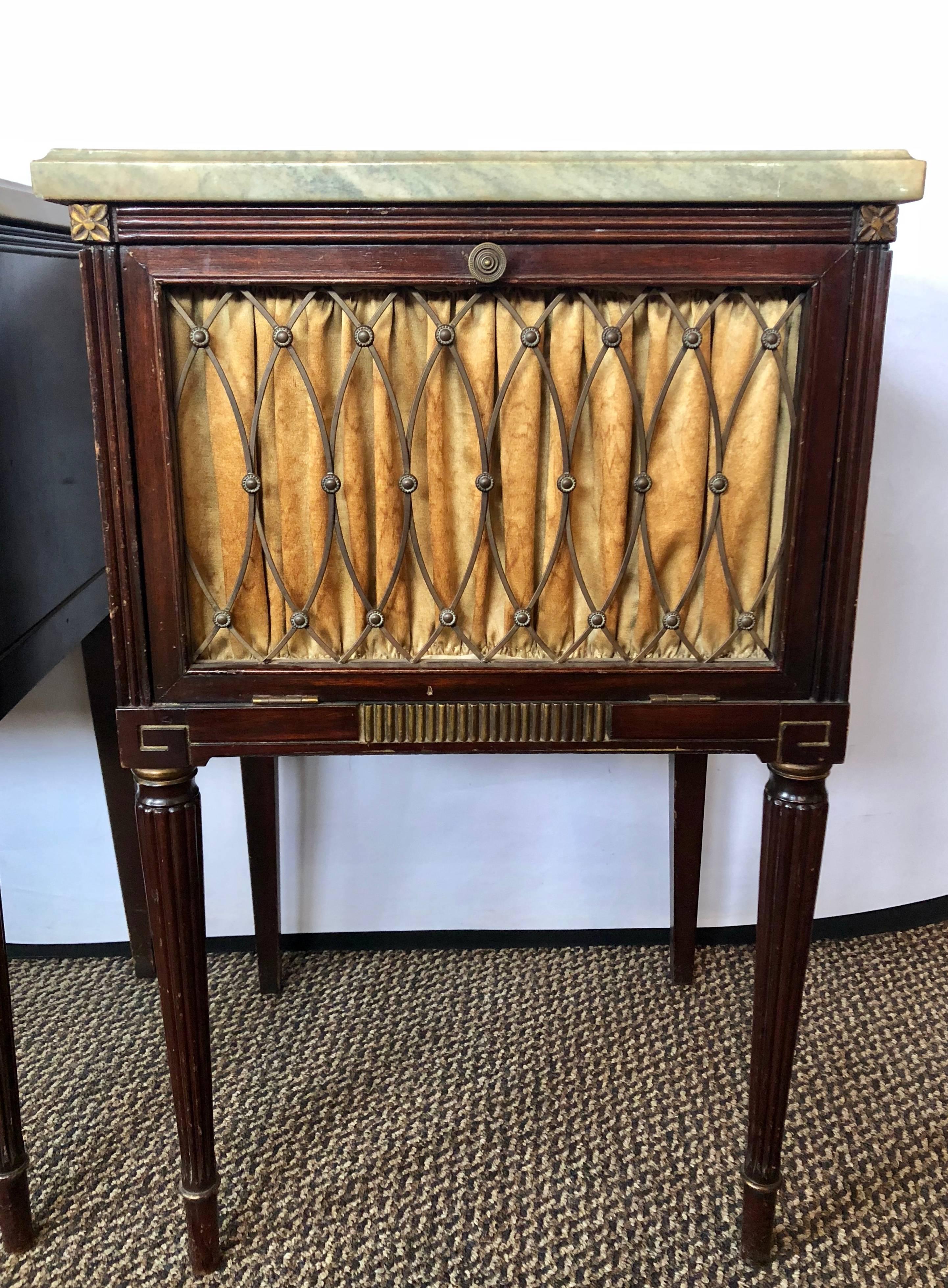 Pair of Maison Jansen mahogany marble-top bed stands side tables each with a drop front door having a bronze galleried face opening into a cabinet interior. The apron having a bronze cookie cutter Front Design on Louis XVI stylized legs. The white