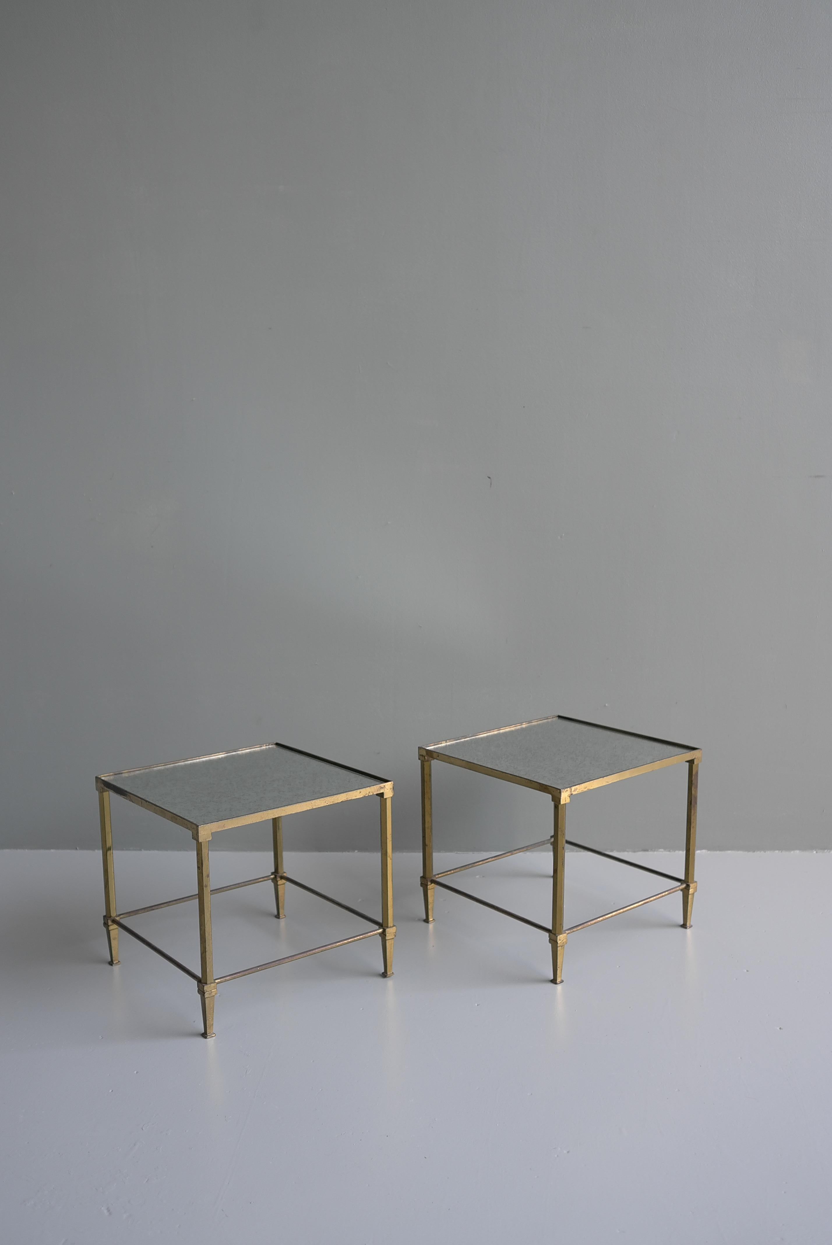 A chic pair of Maison Jansen mid-century French brass with aged mirrored top end tables, France, early 1950's.