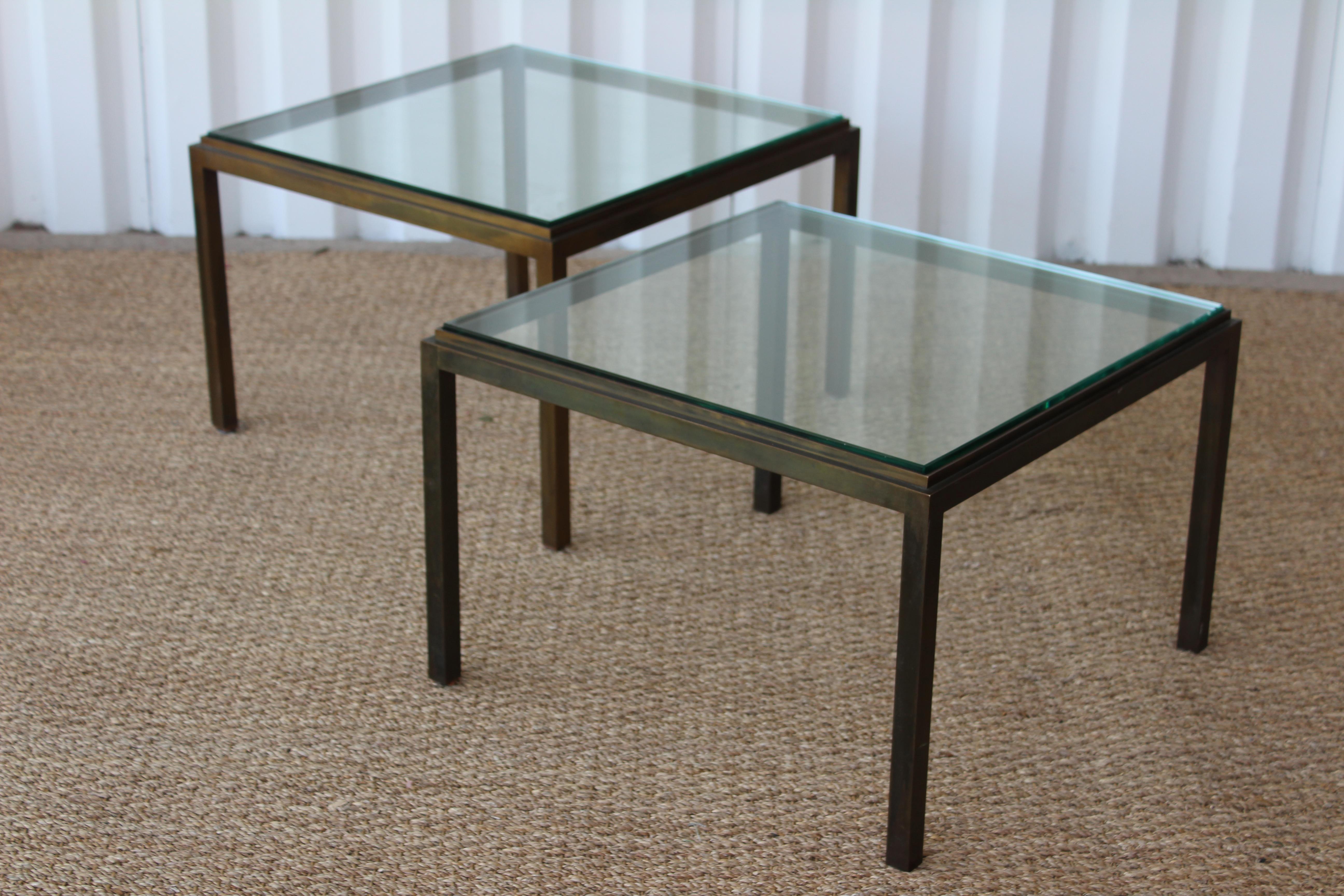 Pair of vintage 1950s bronze tables with glass tops. In the style of Maison Jansen. Sold as a pair. Pair them together to use as a coffee table, or use them as side tables.