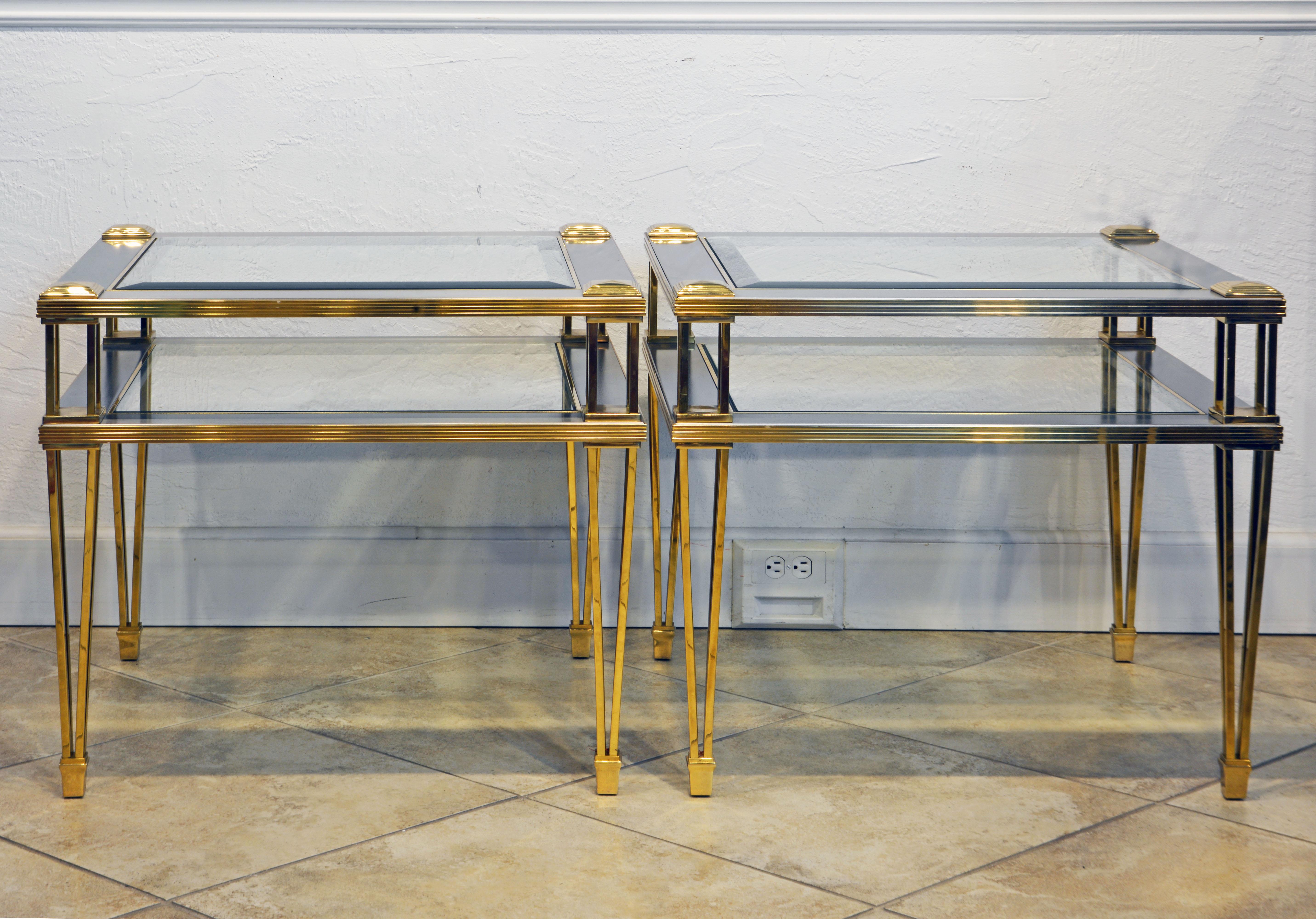 These elegant two-tier Maison Jansen style tables feature brass rod skeleton frames, brushed steel panels with beveled glass tops and under tiers. The combination of the brass and steel in a modern design is stunning.