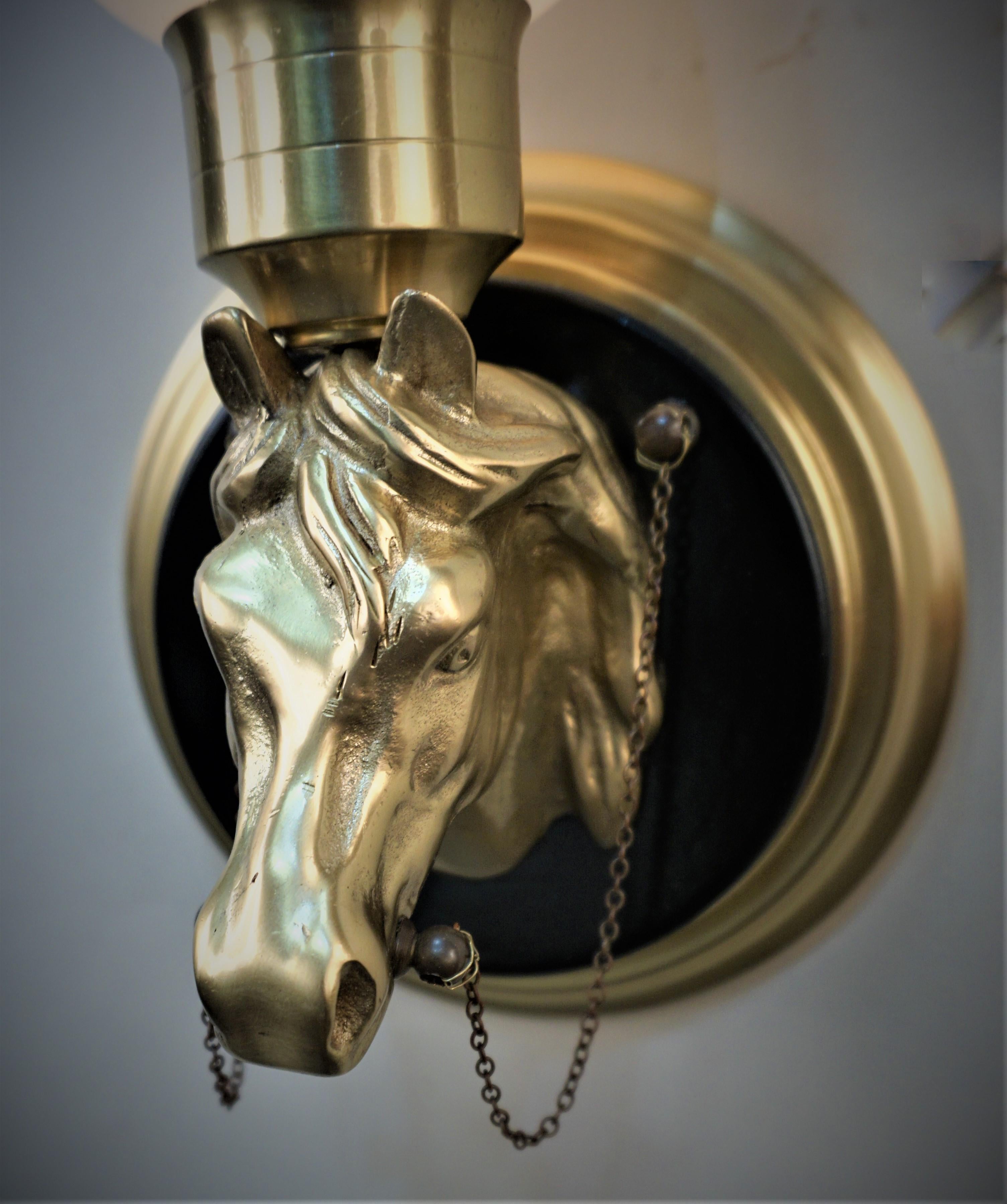 Pair of 1950's bronze horse head wall sconces with white opaline glass shades.
