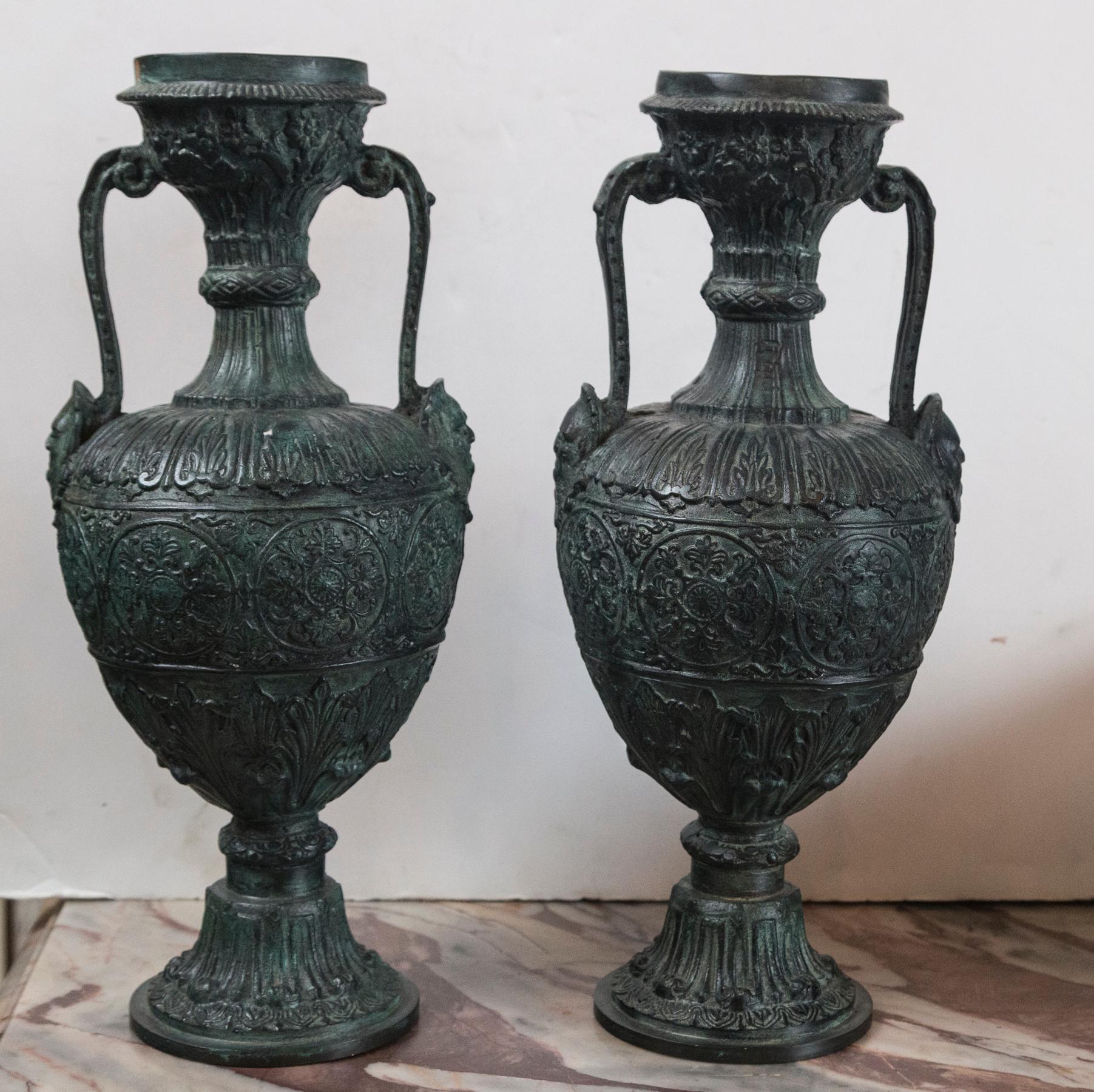 Double handled urns with green/black patina. The base having a 4 inch diameter
The undersides with a Maitland Smith label.
The handles ending at the body with mask decoration. Decorated all around.