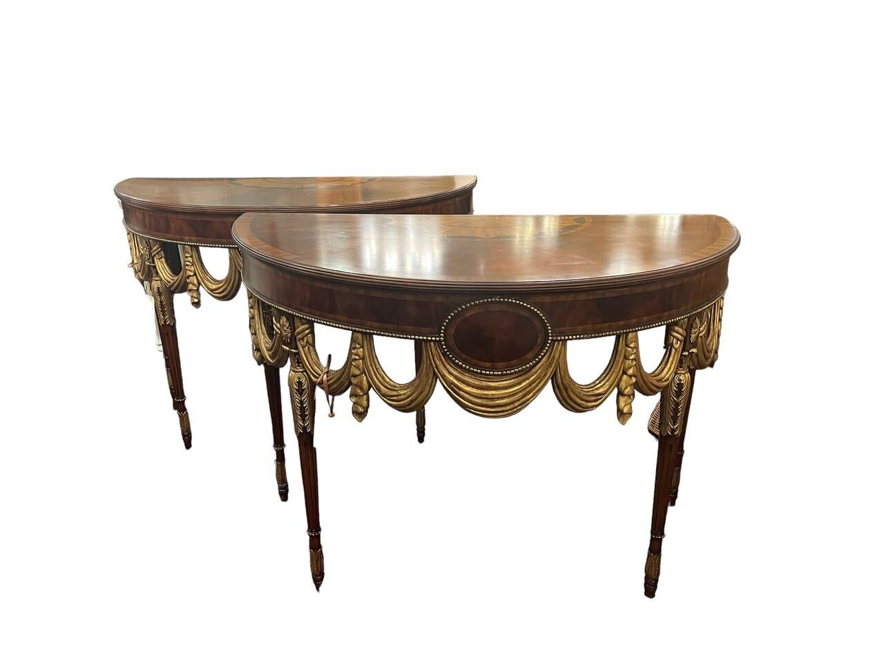 Elevate your space with the elegance of a Maitland Smith half-round inlaid demilune console table. Crafted from crotch mahogany with a sunburst inlaid top, adorned in gold gilt finish, and featuring a drape carved skirt, this piece exudes timeless
