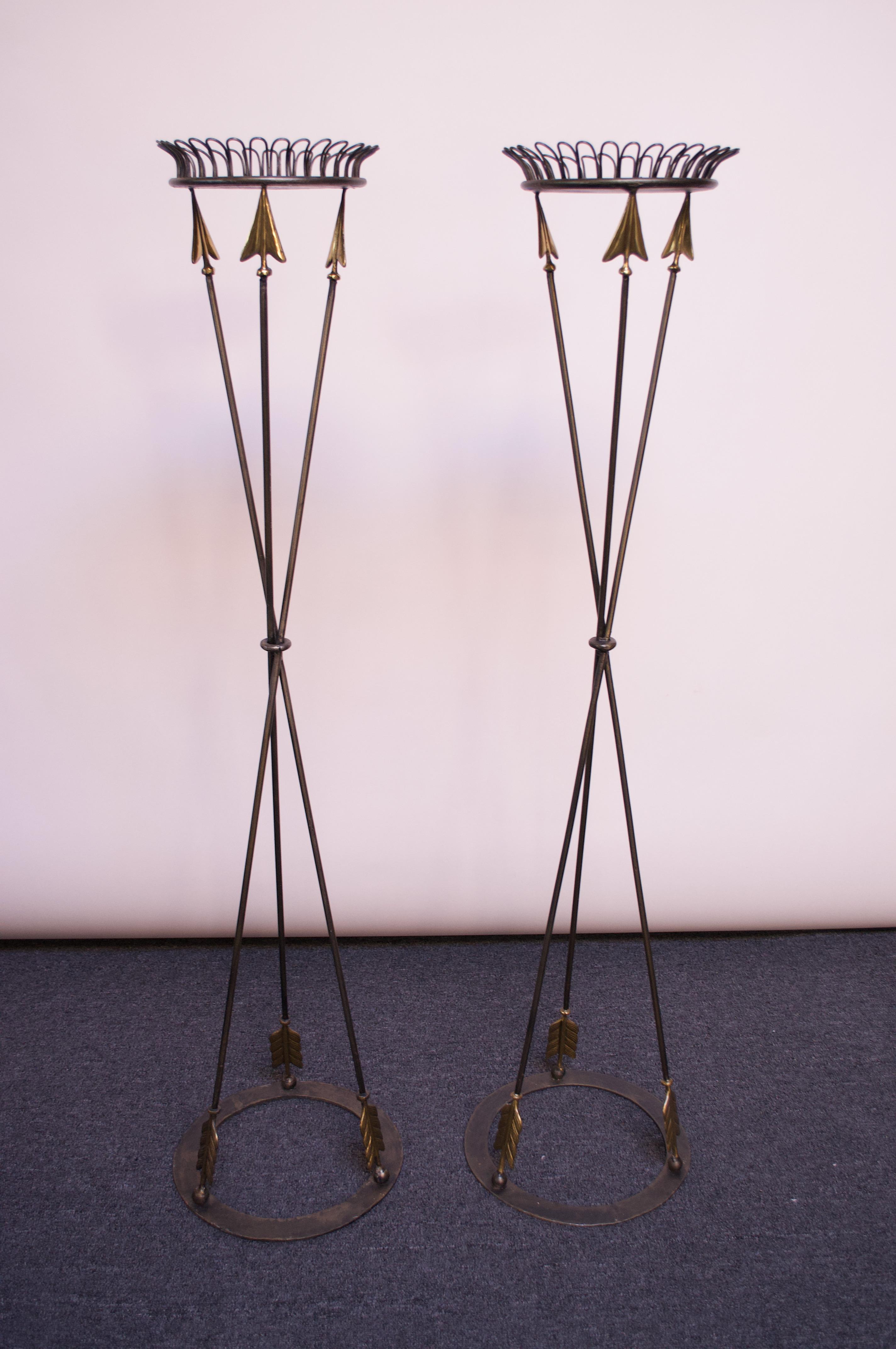 Circa 1980s Maitland Smith Neoclassical-style torchière plant stands with arrow motif. Composed of welded iron with solid brass decoration on the arrow heads and fletchings. 
Surfaces are bordered by a 'loop' design which adds a decorative element