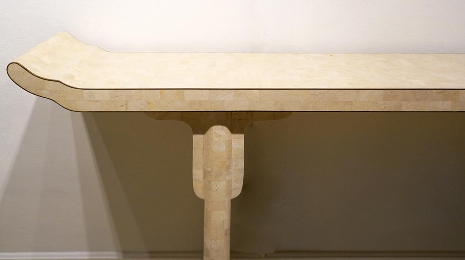 This pair of Maitland Smith style tesselated console tables are designed inspired by Chinese altar tables. They are covered by a mosaic of small travertine marble tiles and the tops elegantly edged with brass. Top craftsmanship.