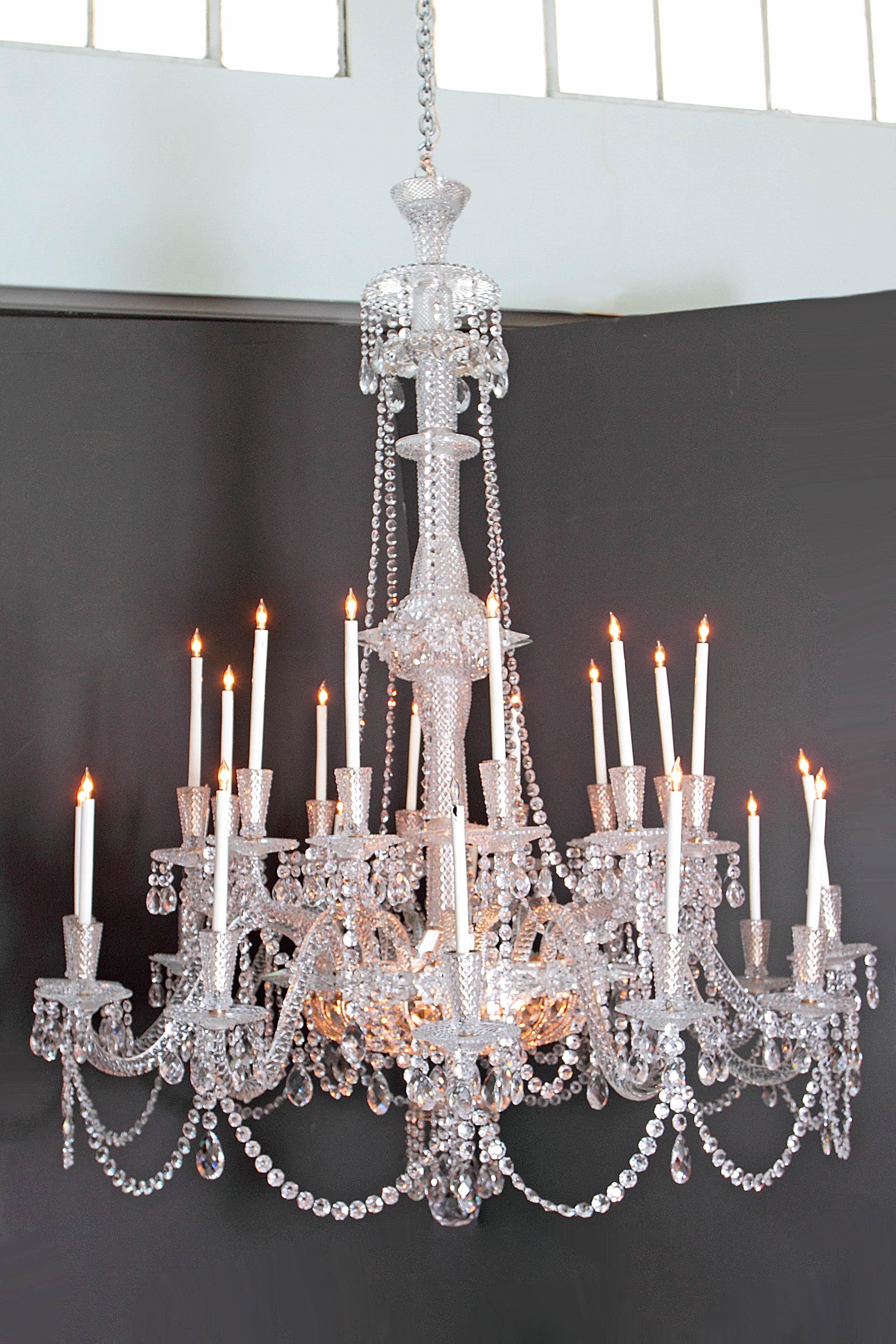 A pair of beautiful grand-scale and well-appointed glass and silver plate Georgian style / mid-Victorian chandeliers. 24 imposing candle arms each contain a single white taper. In the basket or bag at base are six lights or bulbs that light up the