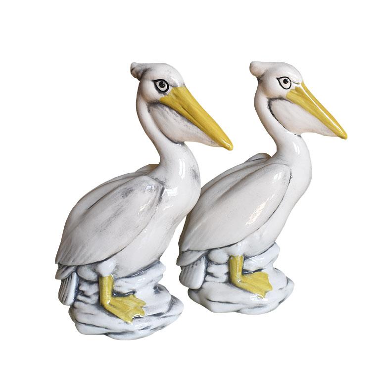 A pair of tall handmade hand-painted ceramic majolica pelican birds. Each bird is glazed in cream, yellow and black. This pair will be fabulous to display on a bookshelf or foyer table. Each bird is painted in a glazed cream, with yellow beaks and