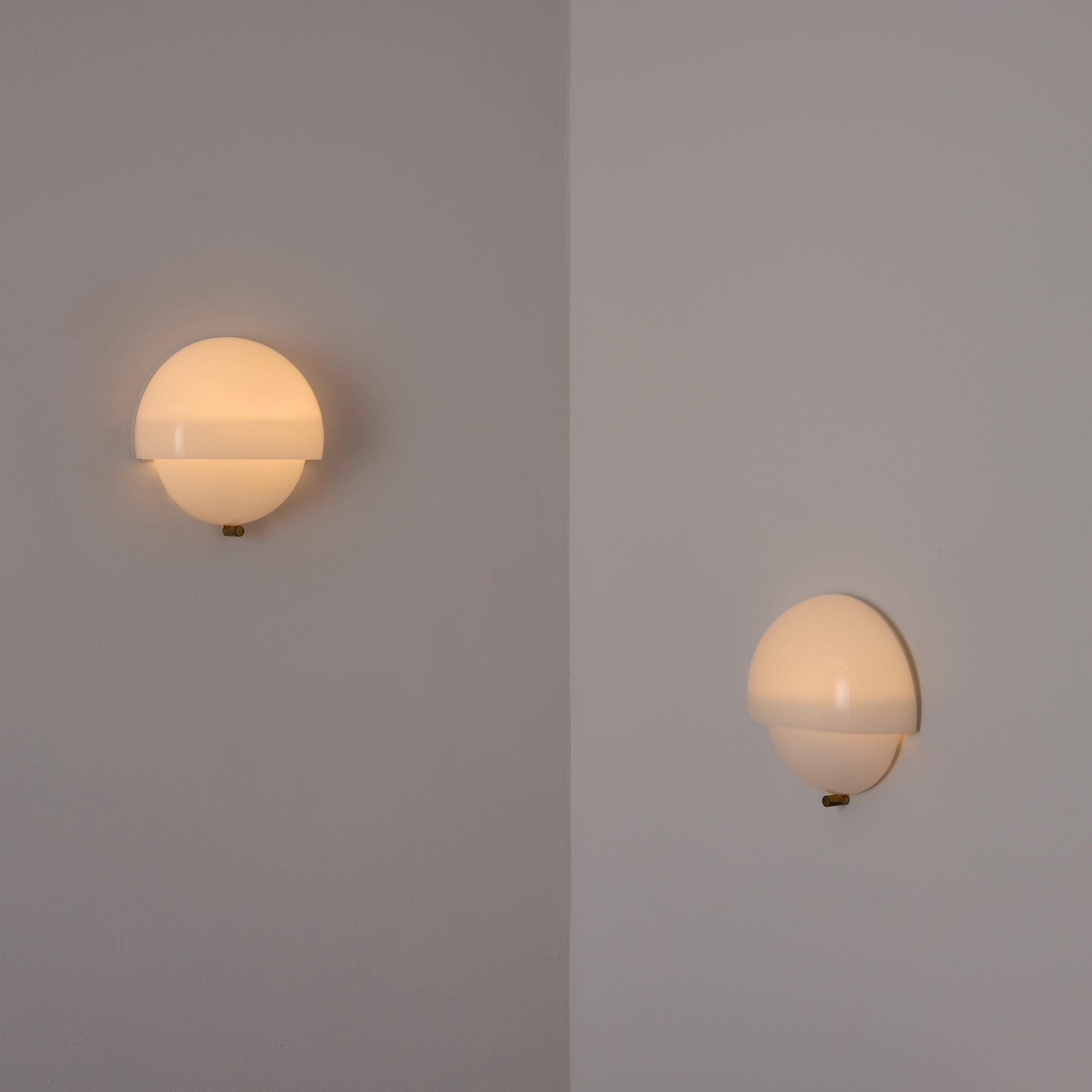 Sconce Mania di Vico Magistretti per Artemide. Progettato e prodotto in Italia, intorno al 1960. Applique minimal a mezza sfera stratificata in delicato vetro opalino. Ogni applique contiene due prese E14, adattate agli Stati Uniti. Si consiglia di