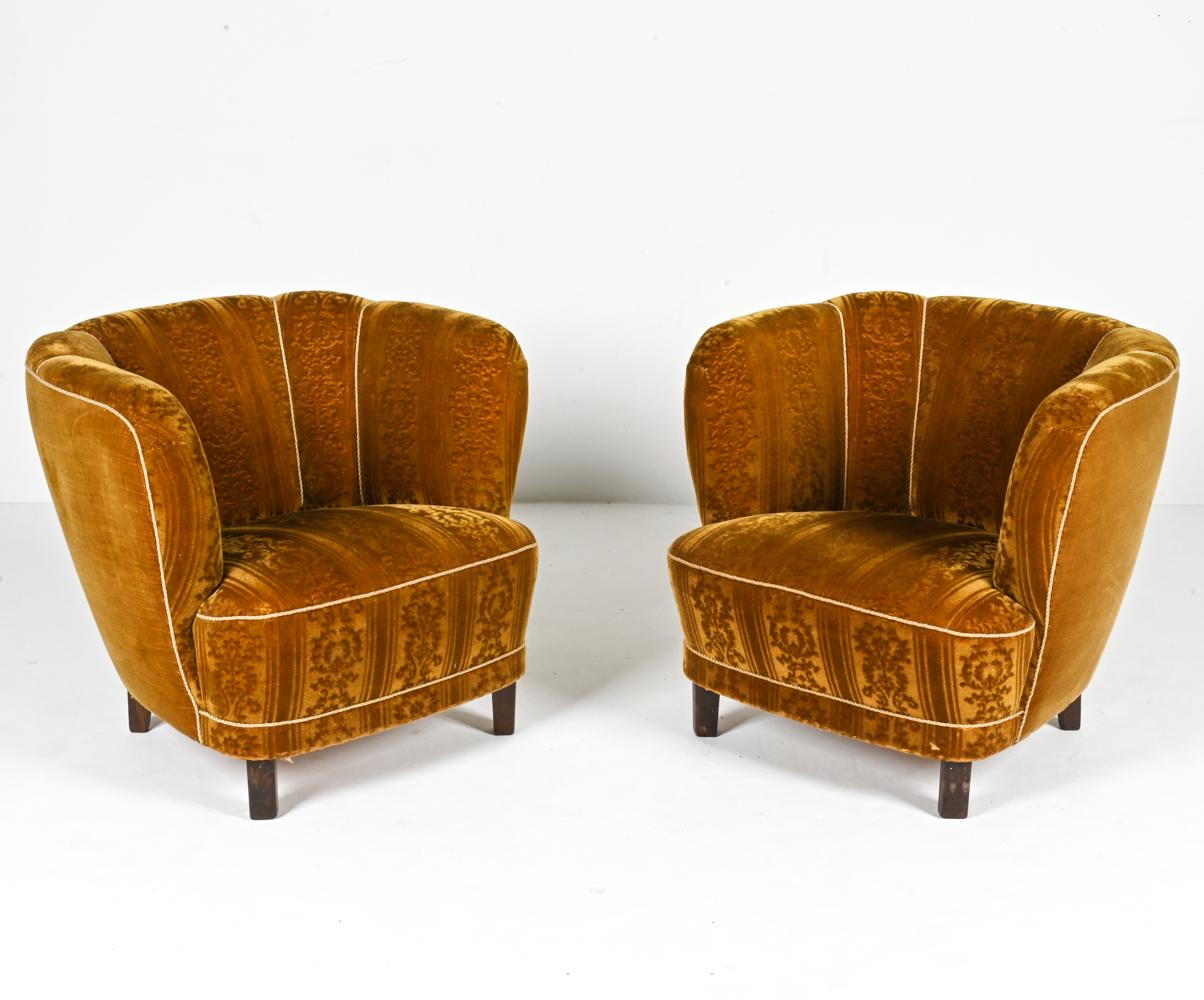 Immerse yourself in an exquisite fusion of history and luxury with this stunning pair of lounge chairs, inspired by the iconic designs of Viggo Boesen and masterfully realized by Slagelse in the 1940s. These chairs are more than just seating;