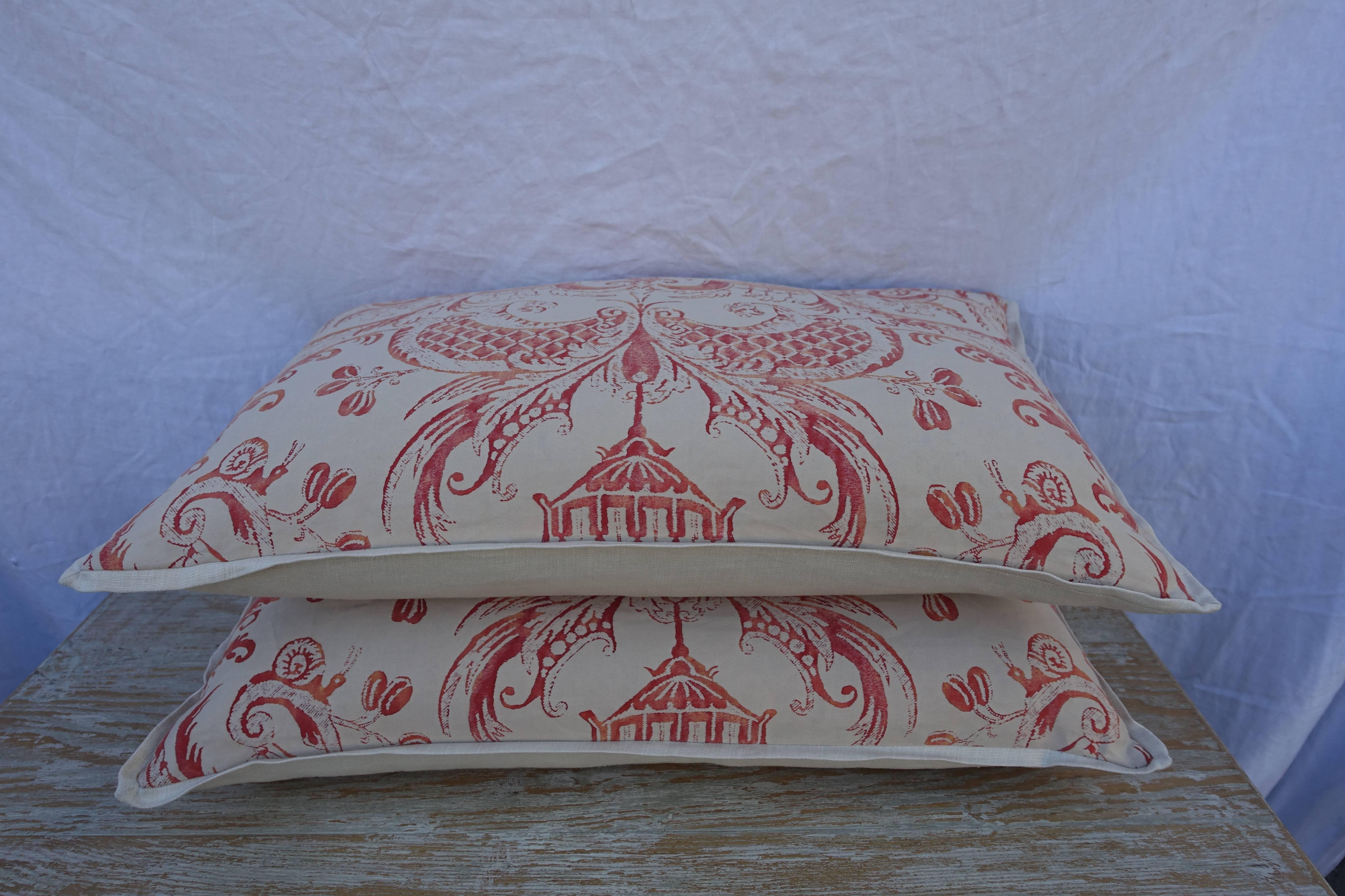 Pair of Manziano patterned Fortuny pillows in tangerine and cream coloration with cream colored linen backs and self welt detail. Down and feather inserts, sewn closed.