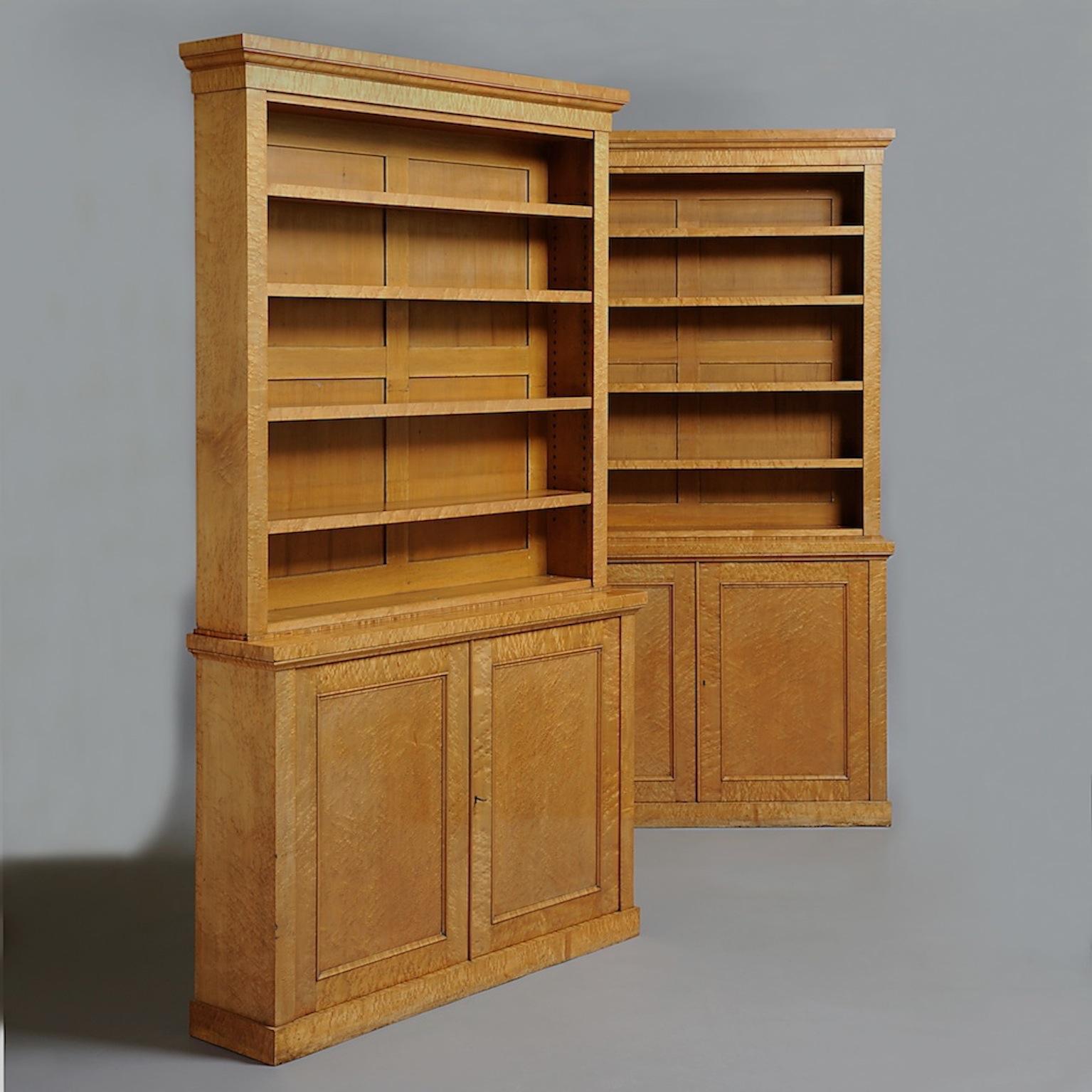 A fine pair of William IV burr maple open bookcases, each with adjustable shelves above two-panelled doors, circa 1830.