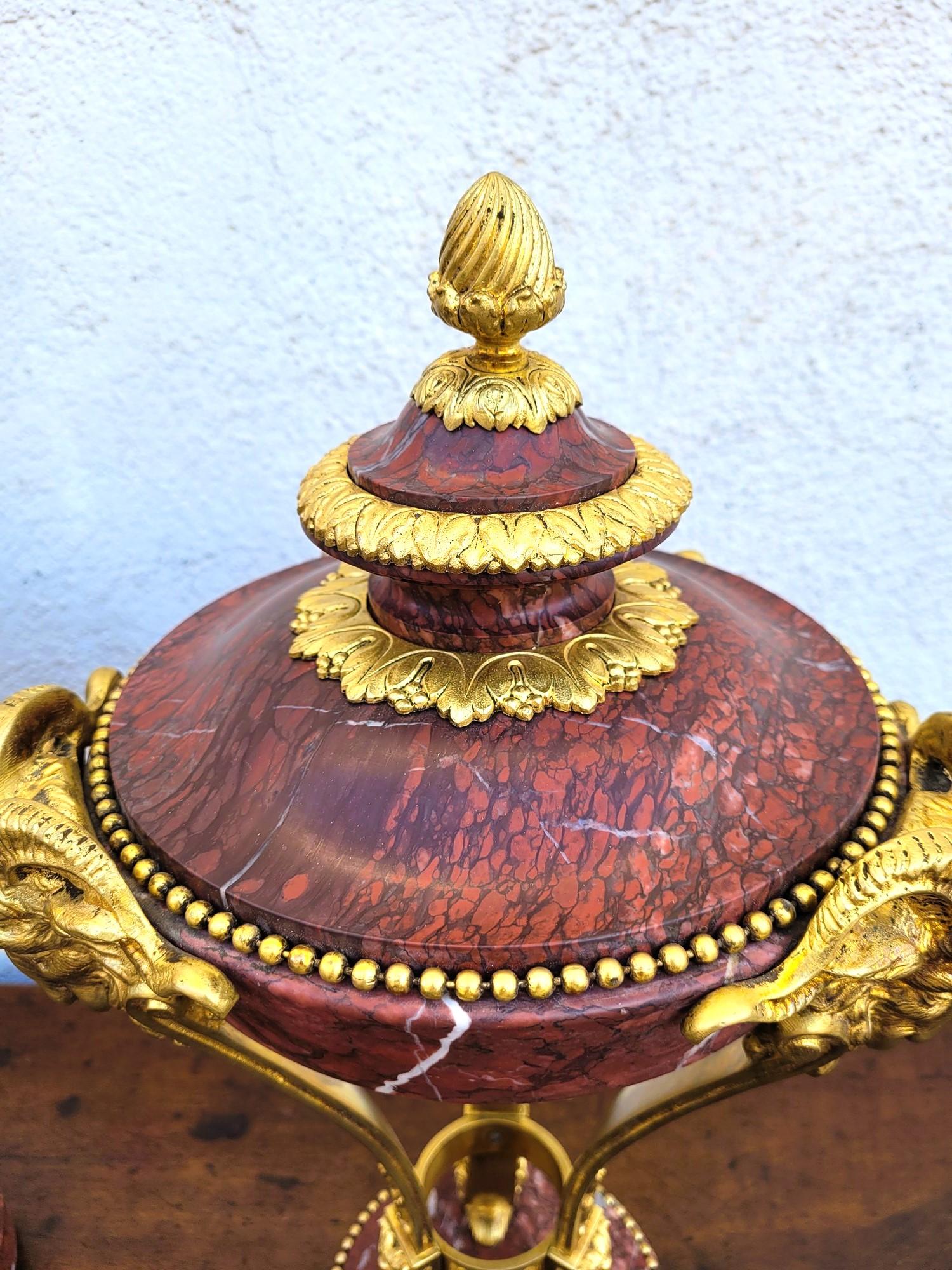Coppia di cassolette in marmo rosso, con ornamenti in bronzo: teste di montone, fili di perle, pigne

Cassolette della fine del XIX secolo, in buone condizioni generali, notare alcuni graffi sul marmo

Altezza 50 cm
Diametro 28 cm circa.
