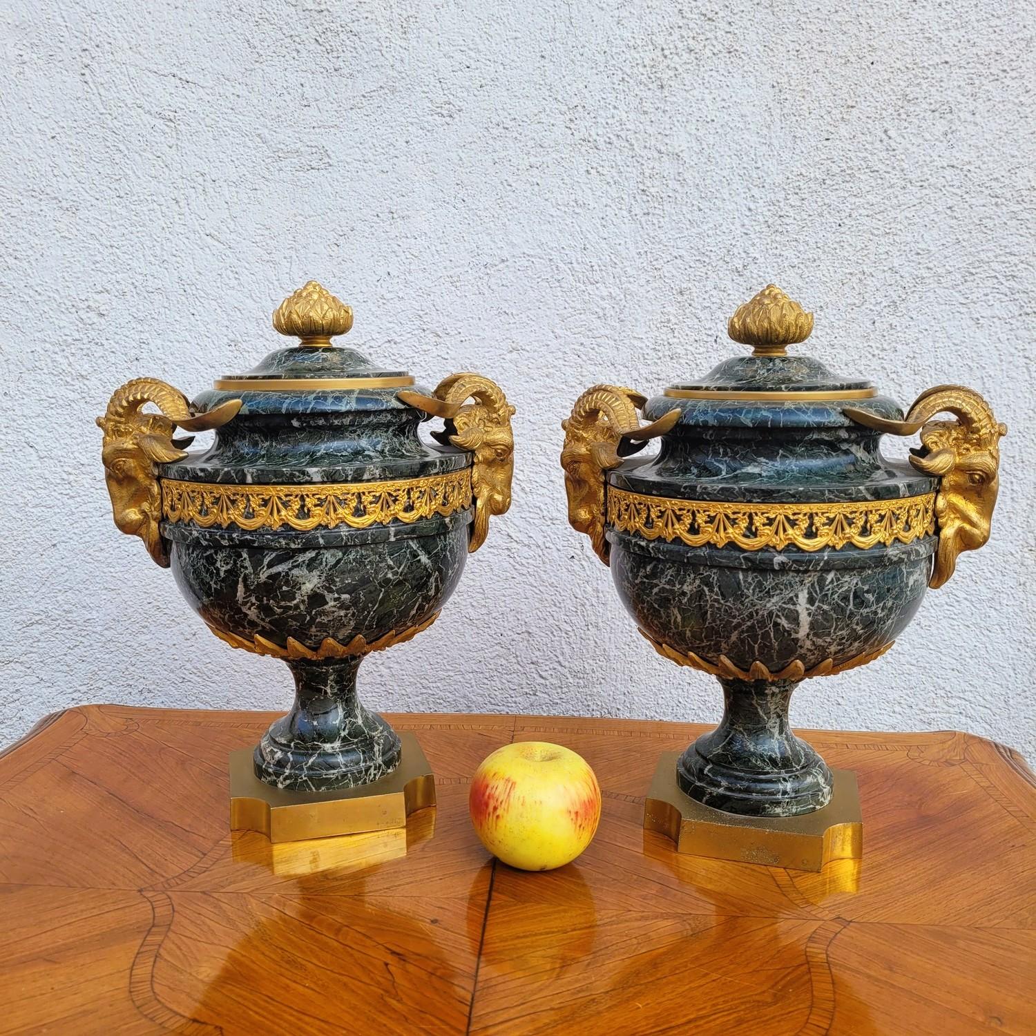 Elegante pareja de cassolettes de mármol verde con vetas blancas, ricamente decoradas con bronce dorado: tapas con piñas, asas laterales que representan cabezas de carnero, frisos calados de volutas y guirnaldas de flores.   

Pequeños desconchones