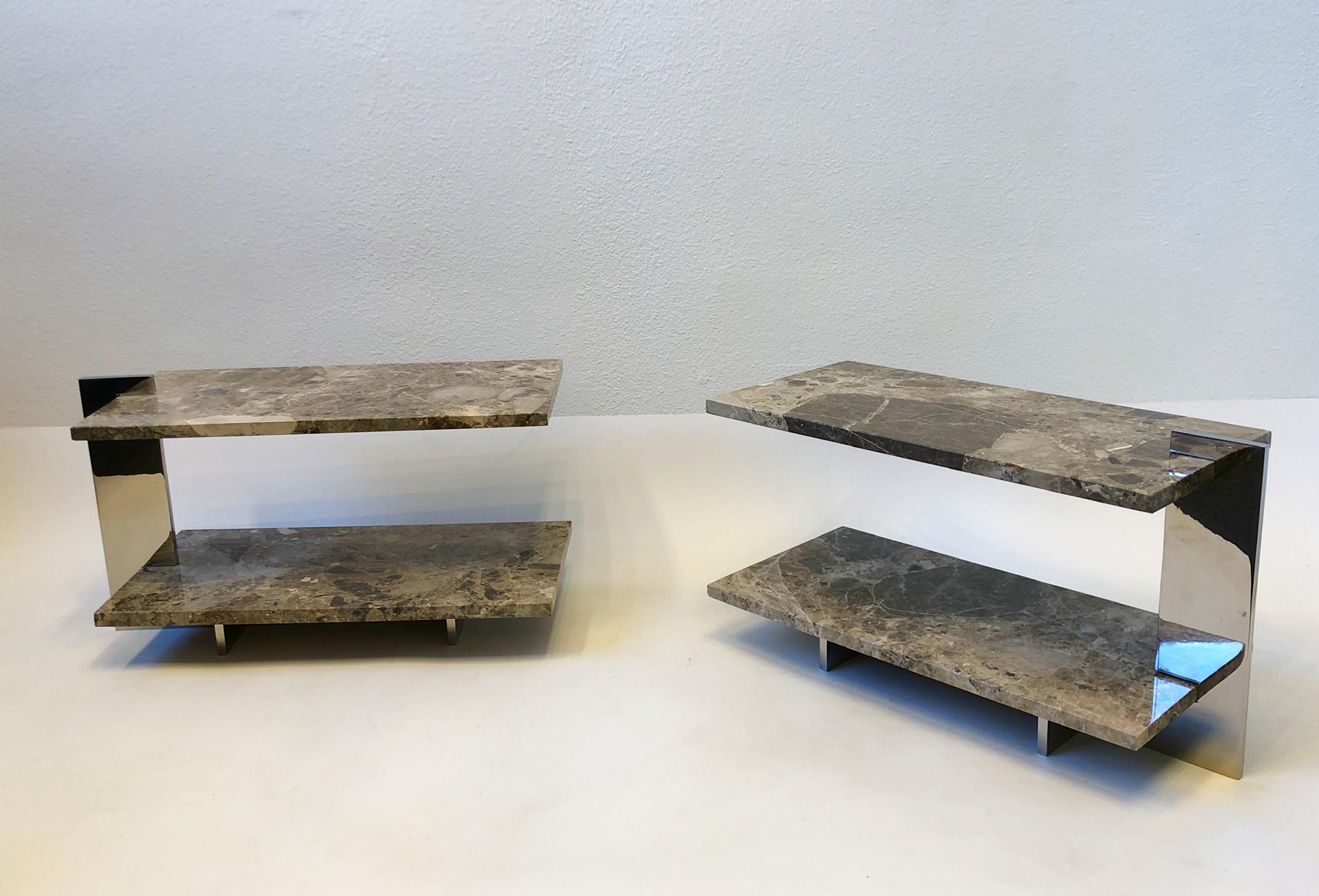 Amazing pair of two tier marble and polish stainless steel side tables. 
The marble piece just sit on the frame. 
In good condition, with minor wear consistent with age. 
Measurements: 12” Deep 26” Wide, 13.75” High to top tier, 3.75” High lower