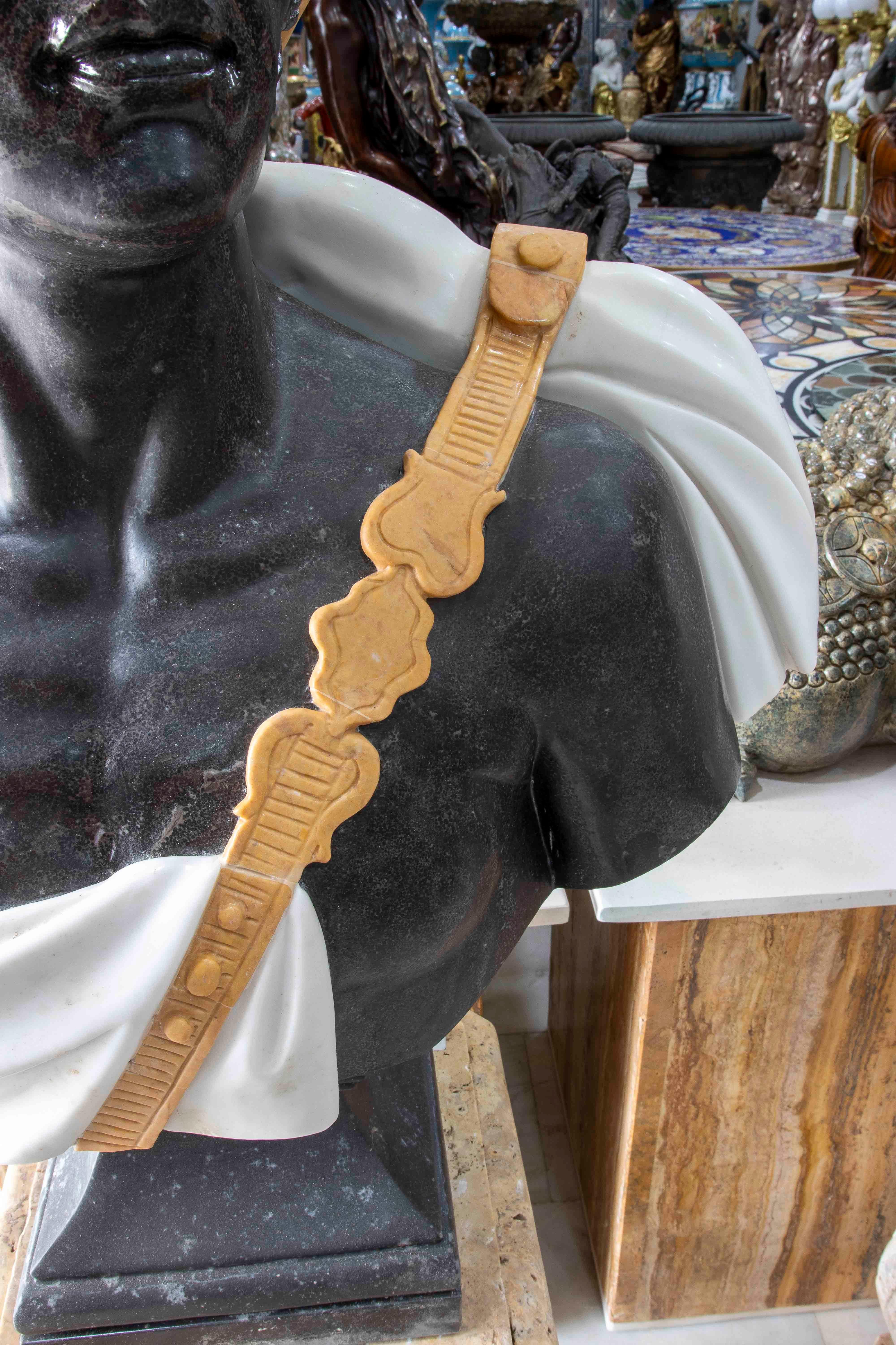 An extraordinary pair of busts carved in multi-colored marble, depicting exotic figures wearing hats crowned with feathers. Each piece is masterfully crafted in different types of marble: dark marble skin, white marble garments, a reddish belt, and