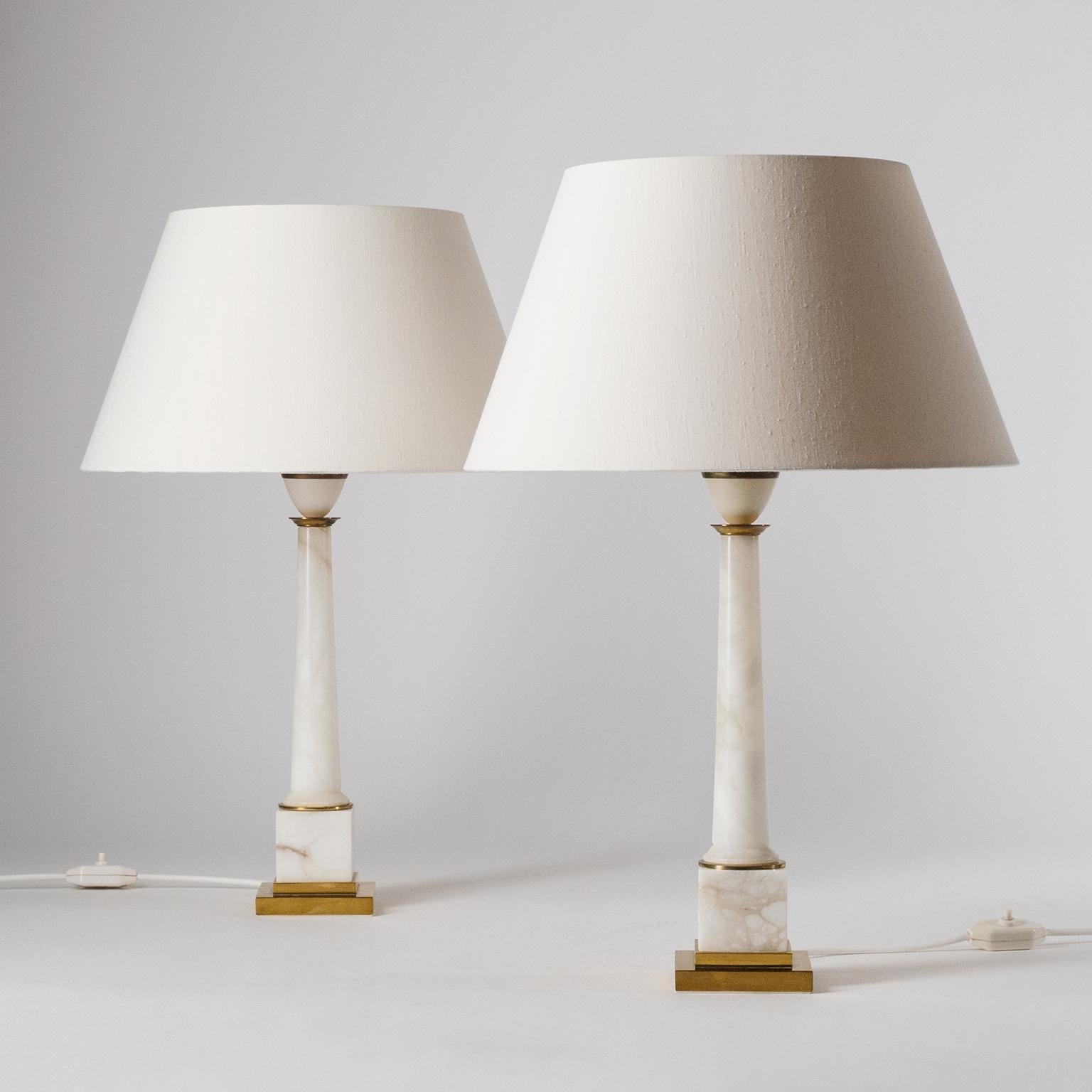 Fine pair of marble column table lamps from the 1960-1970s. Elegant design (Neo-Classical with a Modernist touch) with brass details and original silk shades. Very good original condition with some patina on the brass parts. One original brass E27