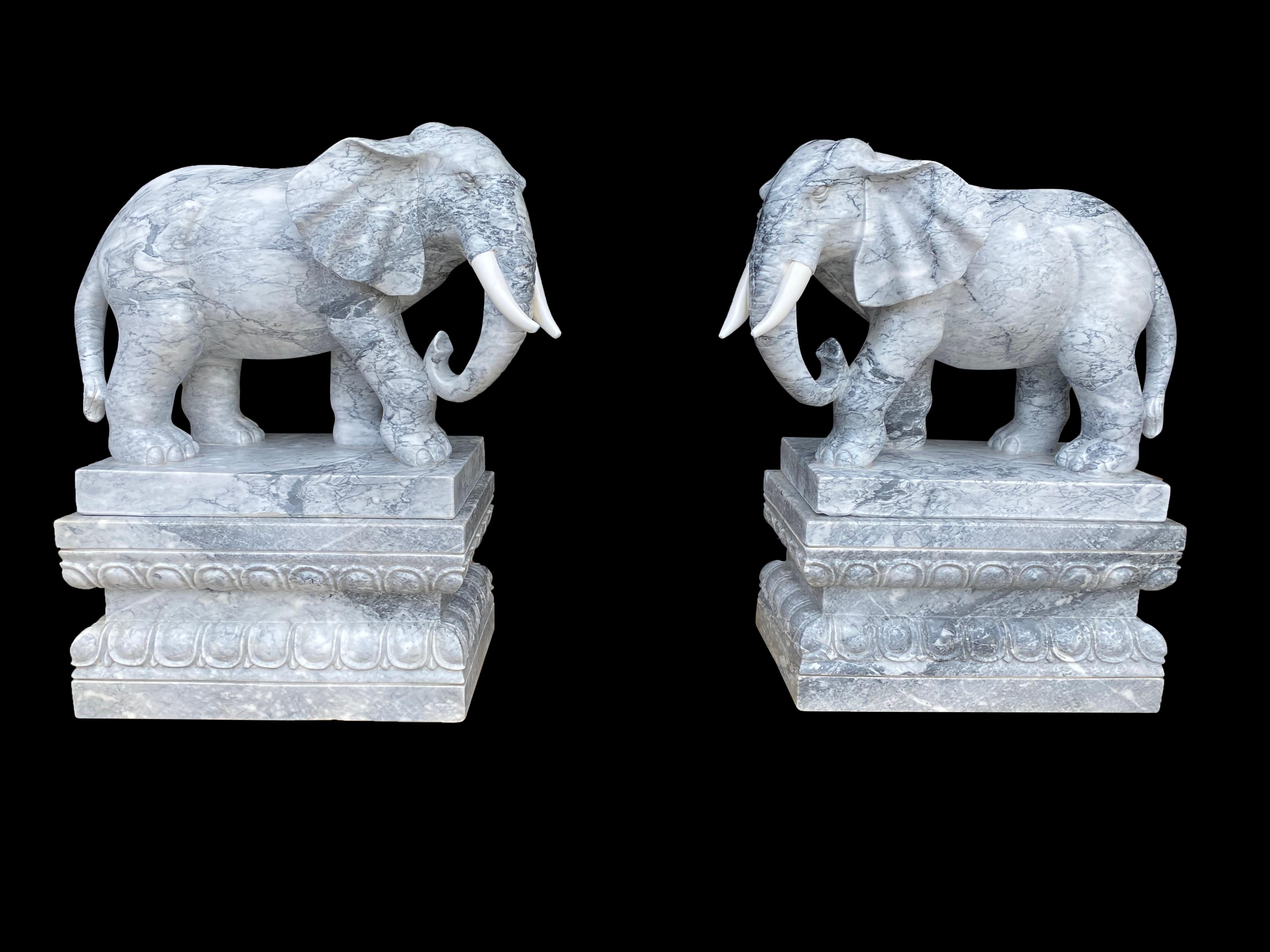 An absolutely stunning and unique pair of marble elephants on plinths, 20th century. The ocean blue veins provide striking colour in this pair, with astounding carved detail. Each elephant is solid marble, and stand on solid marble bases. Perfect