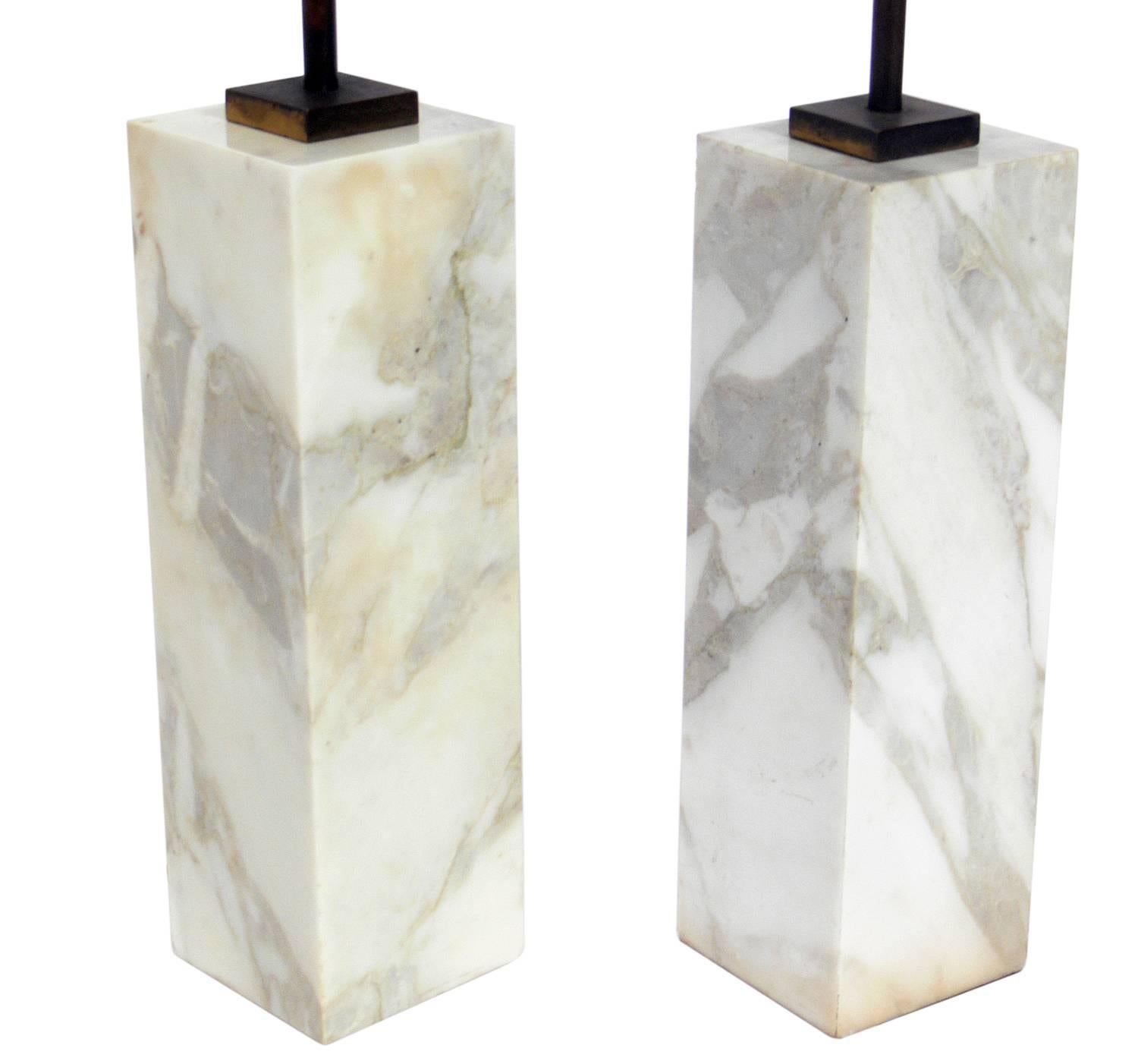 Pair of marble lamps, designed by T.H. Robsjohn Gibbings for Hansen, American, circa 1950s. They are an ivory color marble with light grey and tan veining and the brass fittings retain their original patina. They have been rewired and are ready to