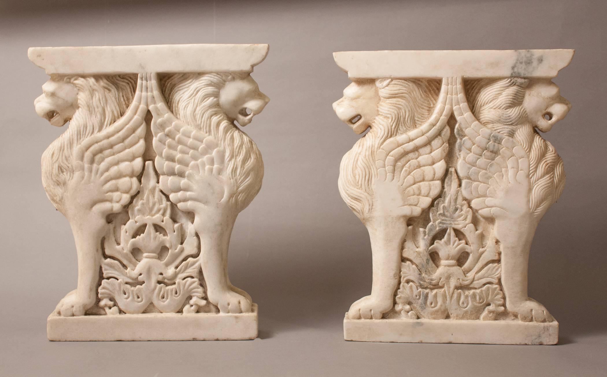 A pair of hand carved white marble bench supports, with attractive veining, that features winged lion sentries and an attractive carved centerpiece relief. With a complementary slab of marble or stone on top, they will make a beautiful bench for a