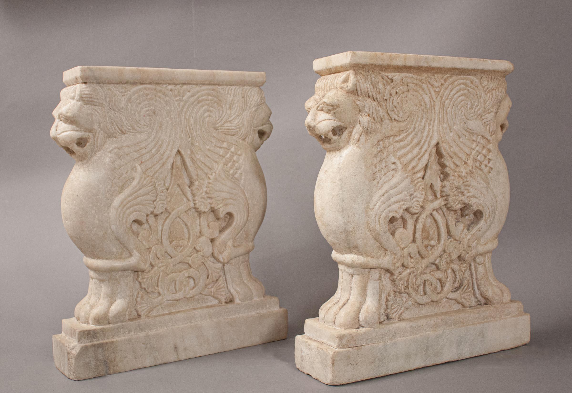 A beautiful pair of hand carved white marble lion bench supports with attractive veining. These circa 1950 winged sentries feature a detailed, carved centerpiece relief. With a complementary slab of marble or stone on top, they will make a beautiful