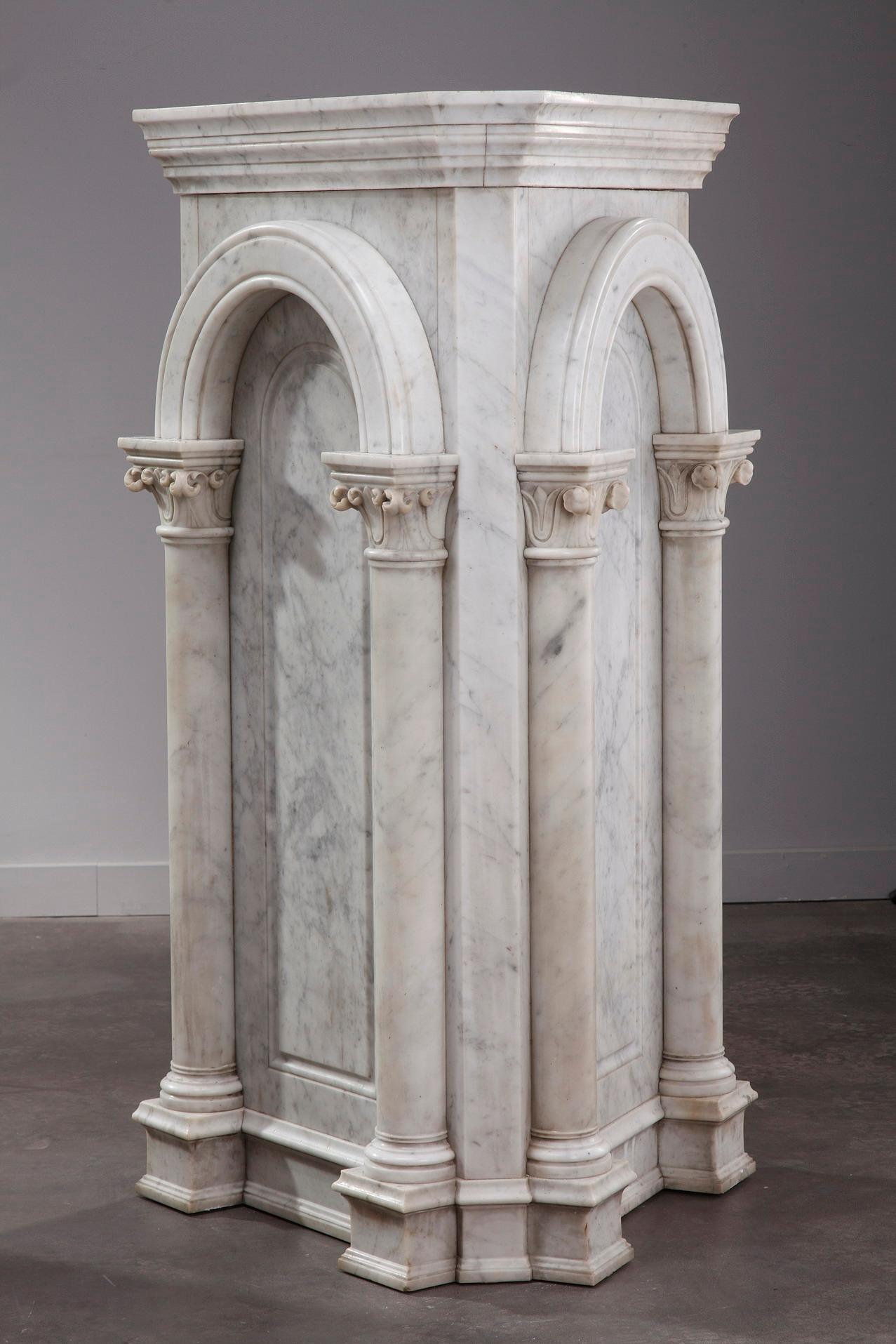 Mid-19th century pair of neoclassical white marble pedestals designed in an architectural manner. The entablature of each stand is supported by an arch, and the arch supported by two columns with Corinthian capitals. The scheme is classical,