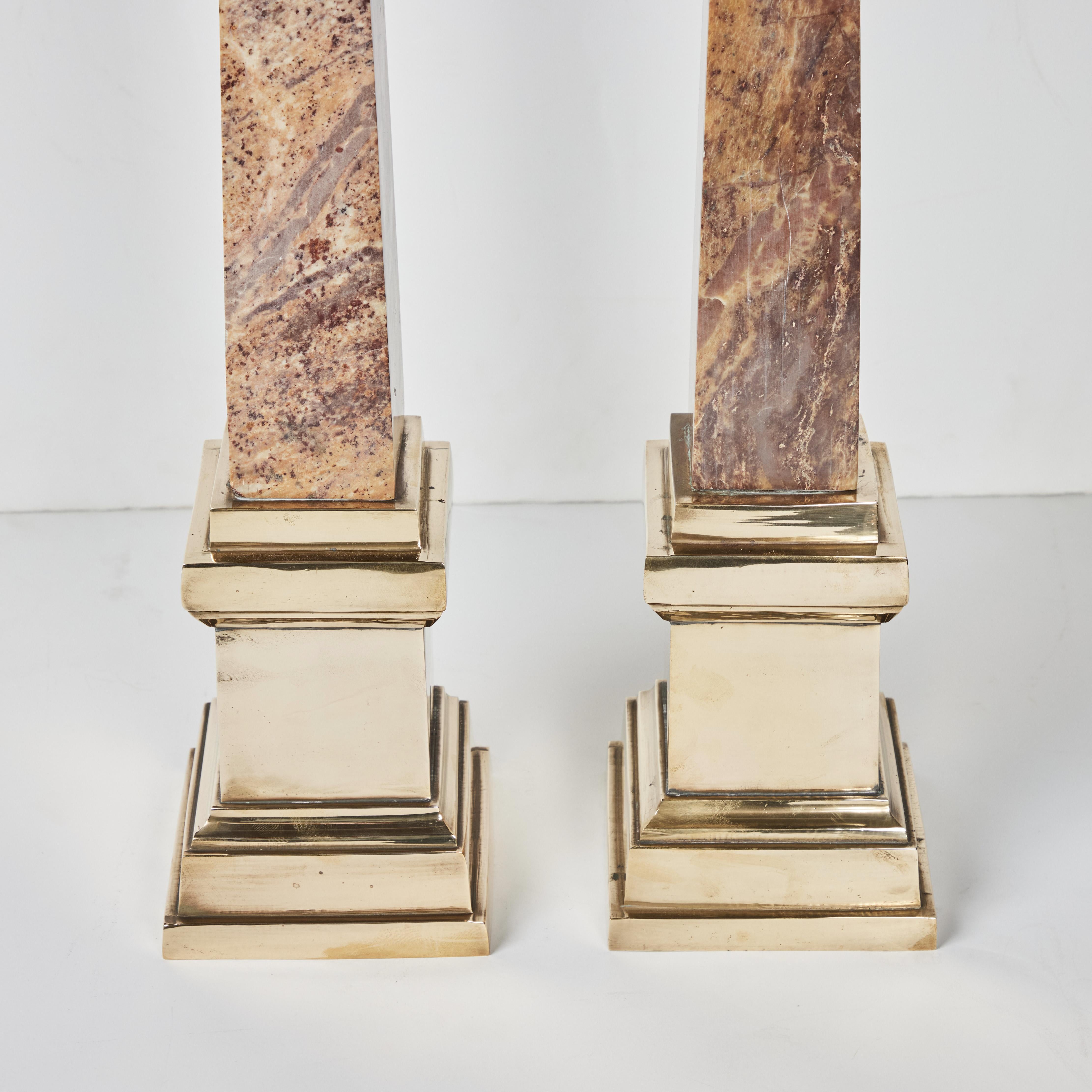 A pair of hand carved, beautifully veined, polished marble obelisks on polished brass bases.
