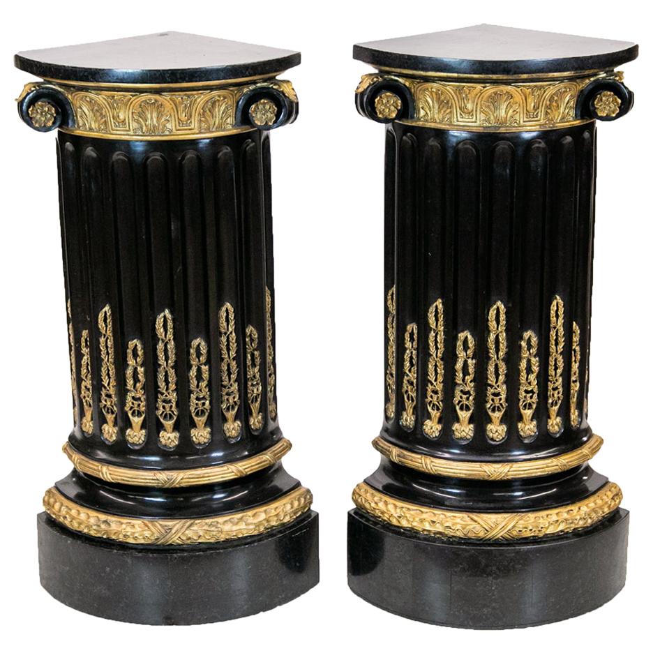 Cette paire de piédestaux à quart de colonne en marbre présente des palettes en marbre appliquées sur le dessus et la base. Les sommets sont soutenus par des chapiteaux corinthiens stylisés, dorés et noirs, qui reposent sur des colonnes cannelées.