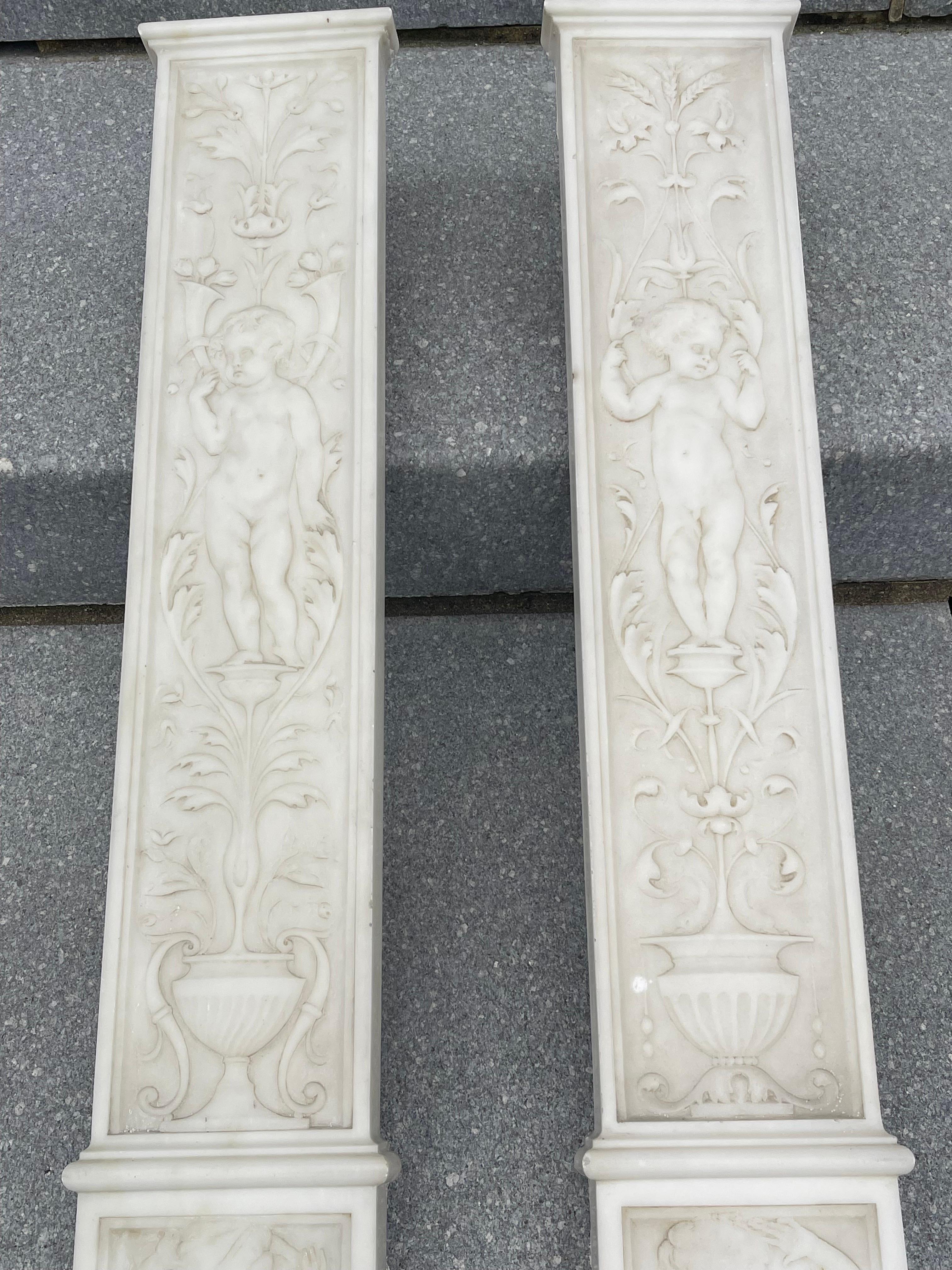 An incredible find. These are a Pair of English Neo-Classical statuary marble reliefs, ca 1820. Depicted are a male and female winged Cupid on the bottom and two pudgy babies rising out of urns  (also male and female) and surrounded by garlands,