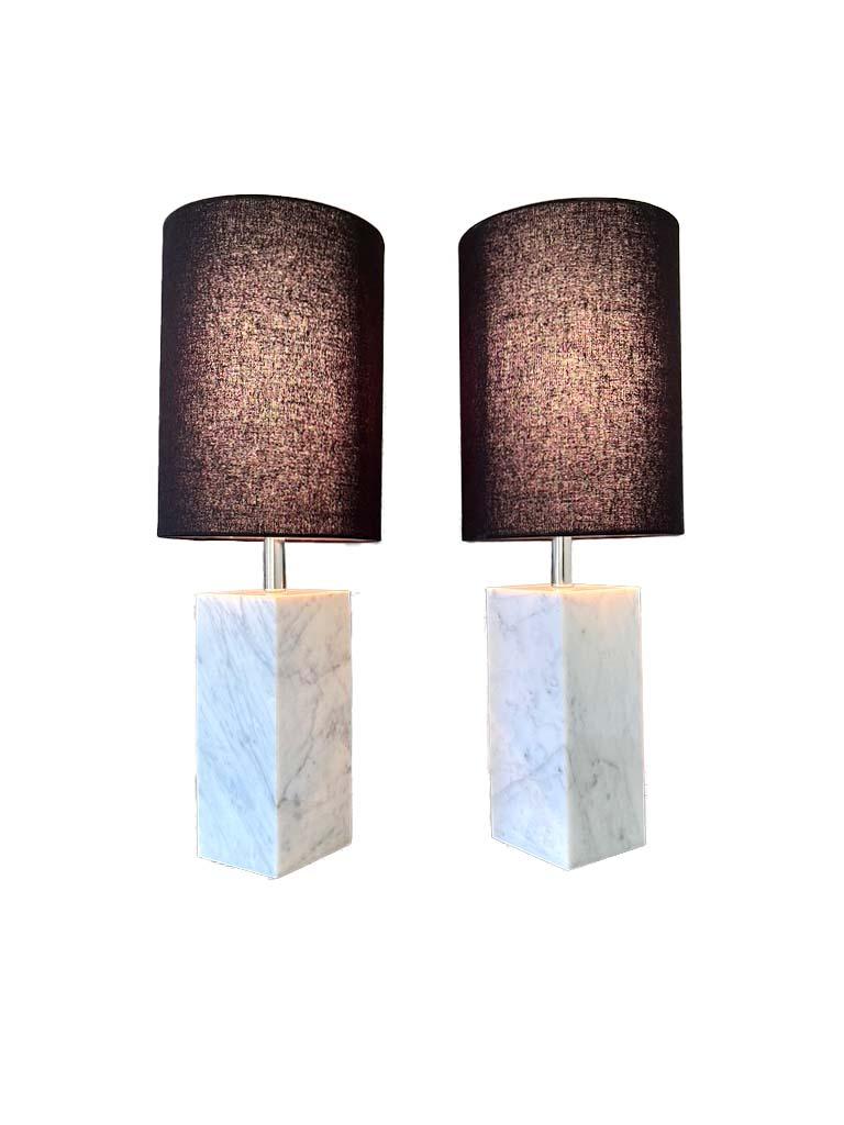 Two white marble square column lamps with chrome fittings and black shades. in the manner of Robsjohn-Gibbings. Beautiful mid-century modern and can mix with many styles.

Overall 22.5” H Base- 4” x 4” x 9.5” Shade- 11”H x 8”W.
 