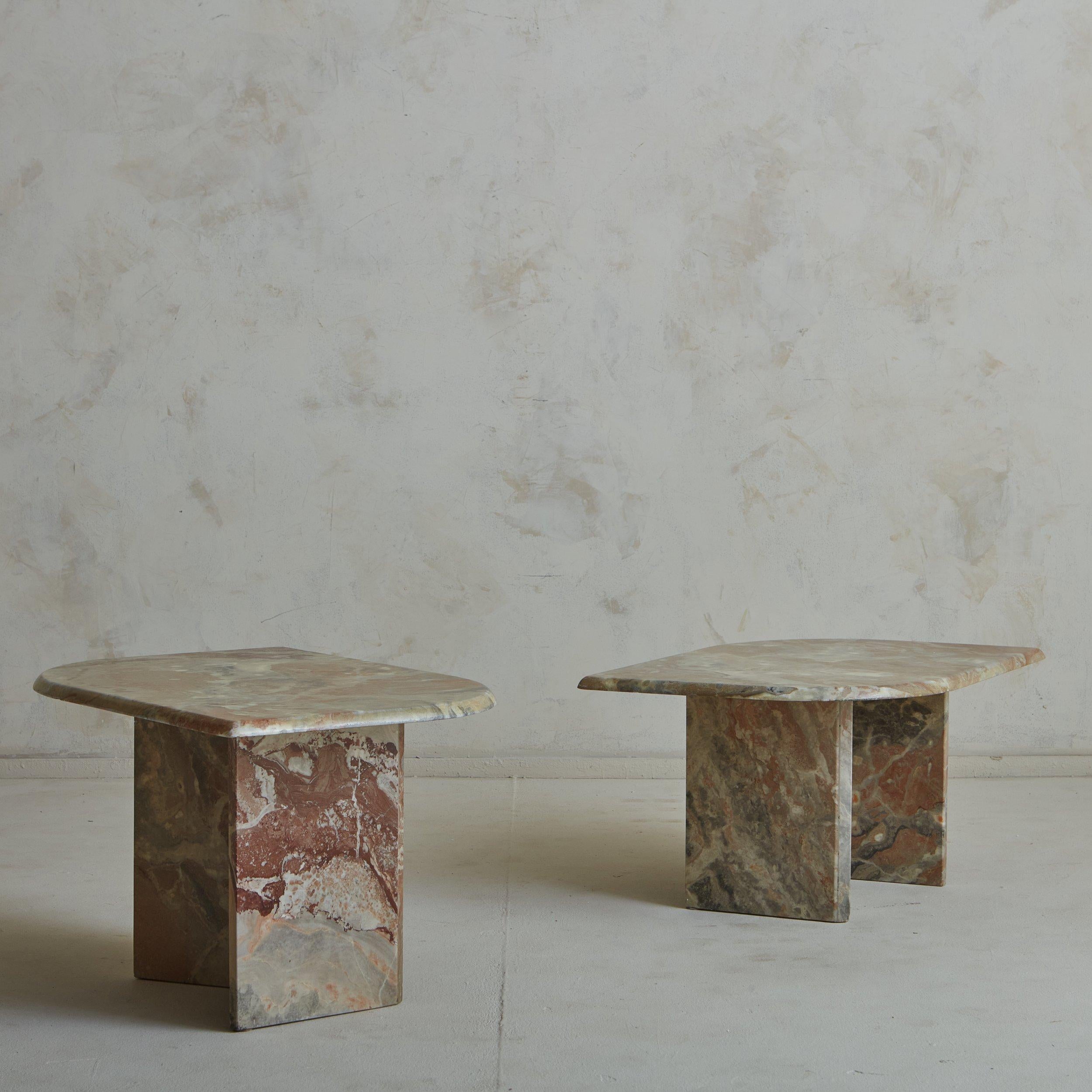 A pair of vintage French side tables constructed with gorgeously veined marble in a range of taupe, cream and rust hues. These tables have teardrop shaped tops and angular bases. One table is slightly shorter than the other, allowing them to nest