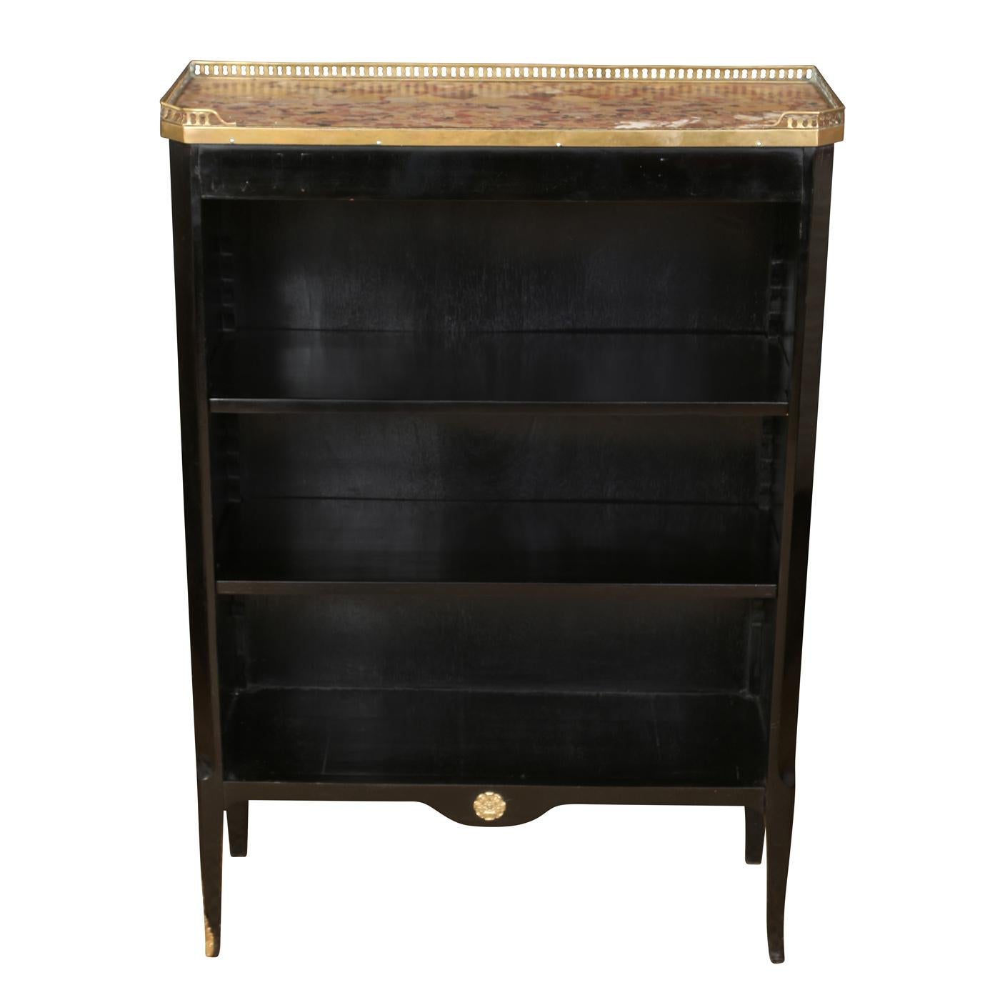 A pair of ebonized Louis XV style bookcases circa 1940, with a coral tone marble top and brass gallery and ormolu mountings to feet and apron.