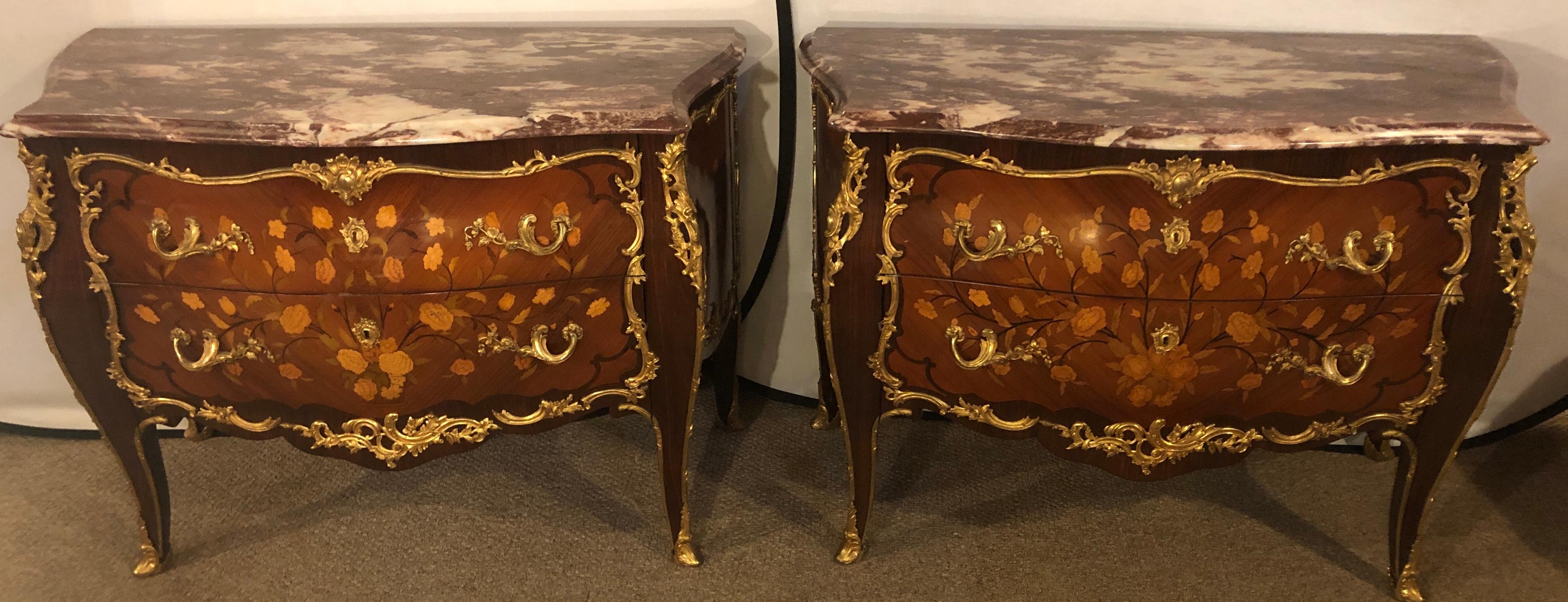 Pair of marble-top bronze mounted bombe floral inlaid Louis XV style commodes. Each of these spectacular custom quality commodes have full bronze shoes leading to a myriad of bronze trim work and floral inlays of kings-wood and satinwood design. The