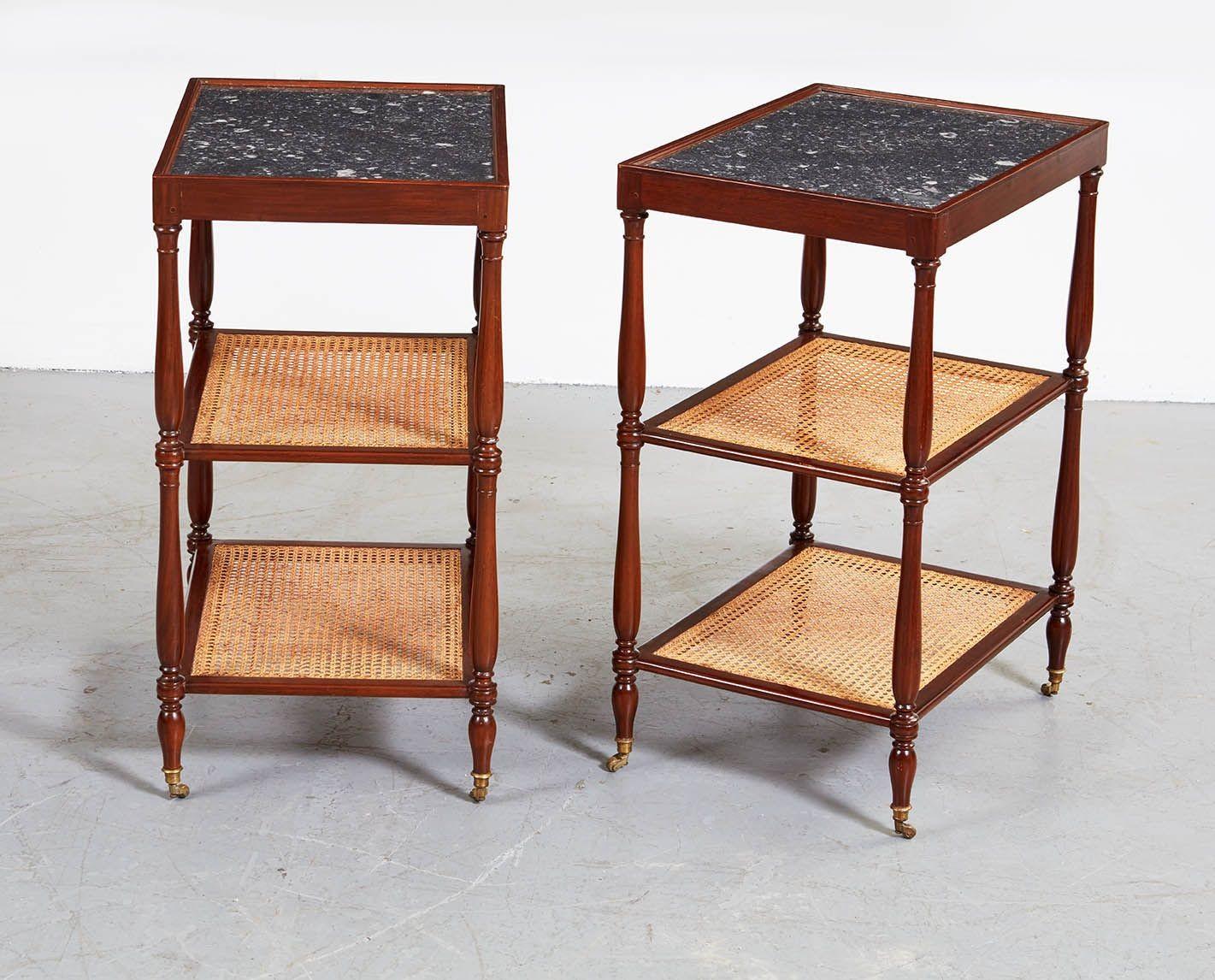 A fine pair of French Directoire tiered end tables with inset fossilized polished limestone tops above two cane shelves in pegged and turned mahogany frame, standing on brass castors.

