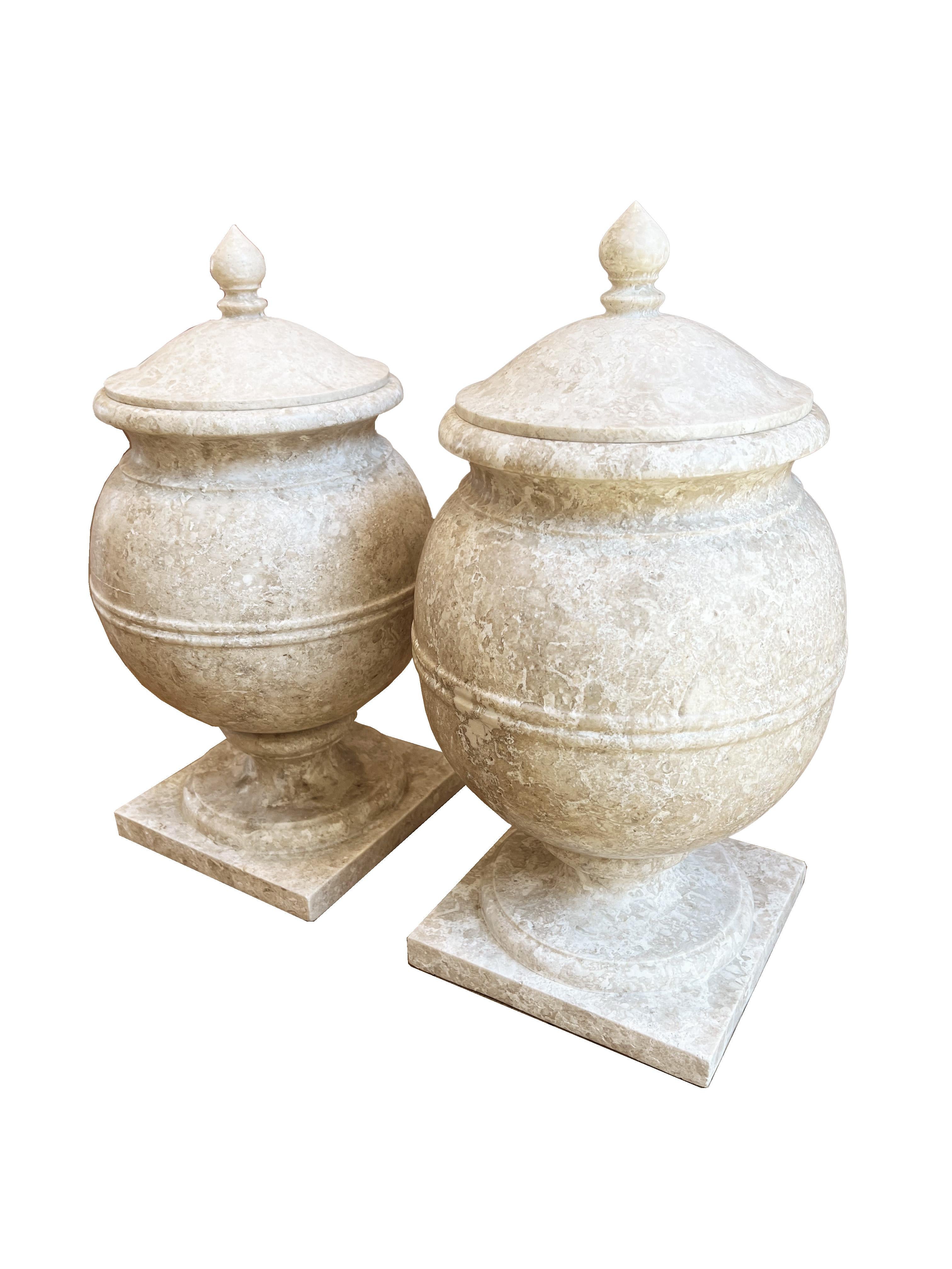 Rehaussez votre maison ou votre jardin avec cette paire d'urnes en marbre, chacune étant un chef-d'œuvre de design et d'artisanat. Ces urnes solides et lourdes soulignent la qualité du marbre et l'habileté avec laquelle elles ont été créées. Les