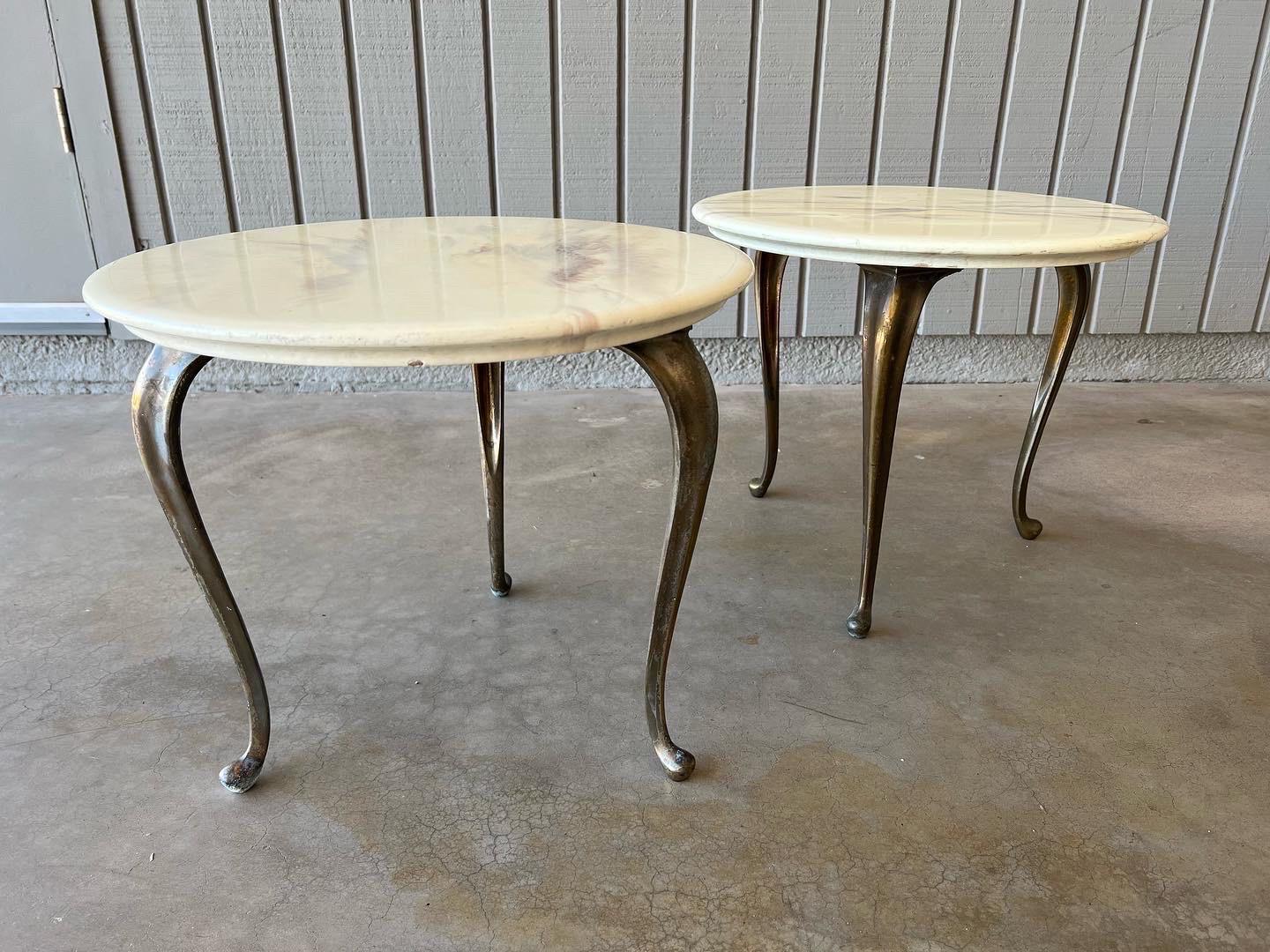 Pair of Hollywood Regency style end tables or plant stands by Marblecraft Company, 1963. The legs are brass, and the tops are faux marble over wood. There is a crack on one of the tops and a couple small chips. They are both labeled on the bottom.