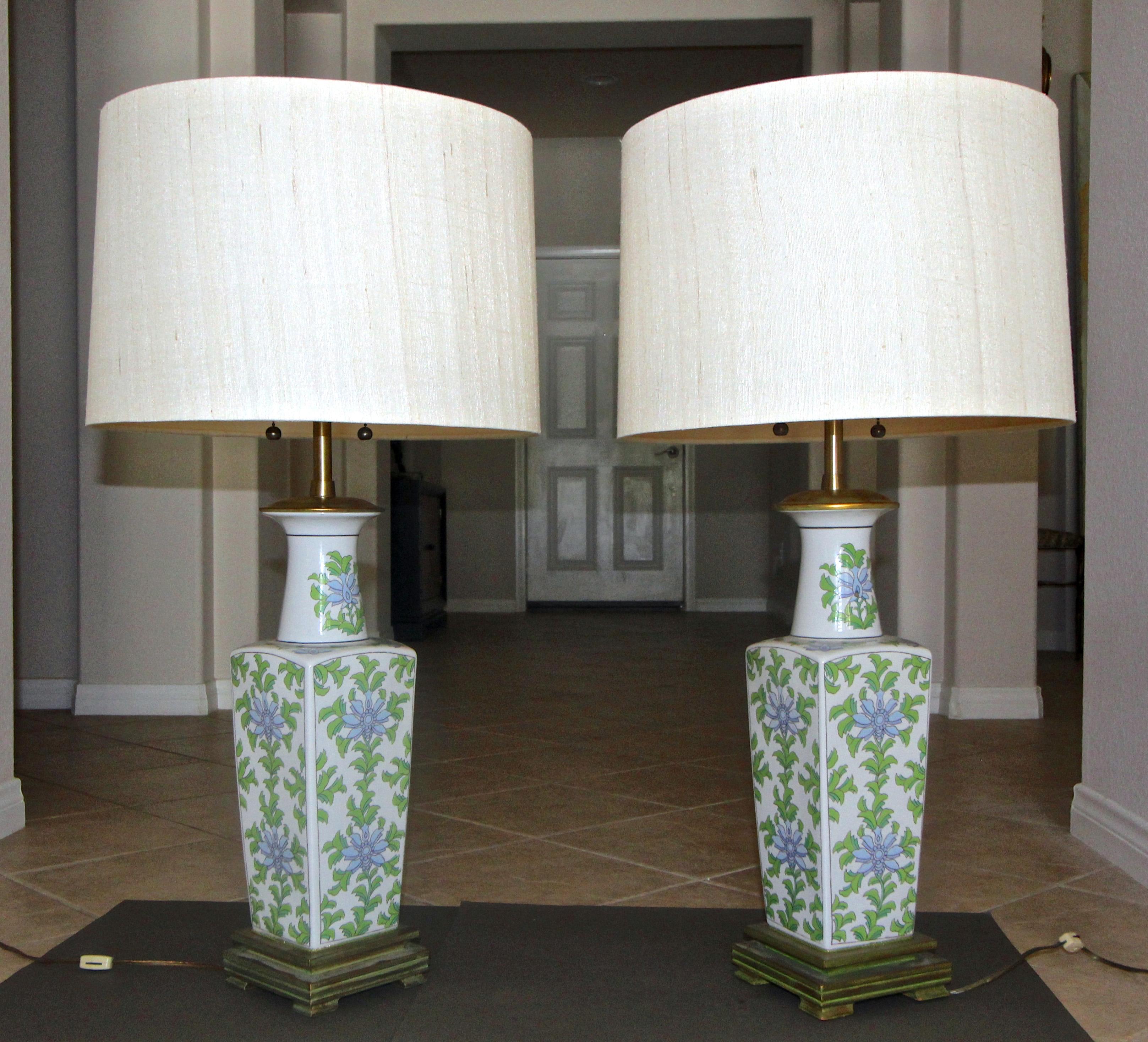 Pair of Asian floral green and lavender motif porcelain table lamps by Marbro. The lamps rest on custom patinated green wood bases. Original solid brass double cluster sockets and fittings. Retains original Marbro label. Shades not included and are