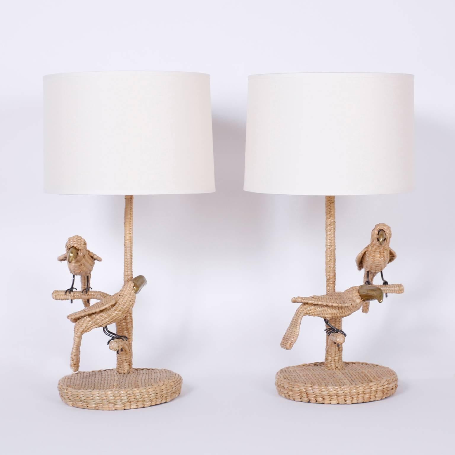 Amusing pair of wicker bird table lamps with a parrot and a toucan perched on each
one. Crafted with reed wrapped over a metal frame. Signed Mario Torres
on a medallion and  your choice of a wicker or linen shade.