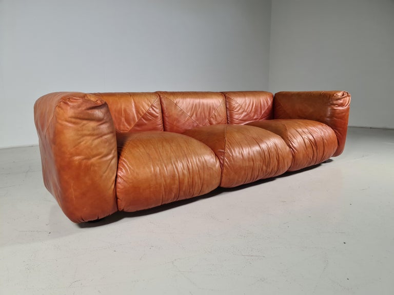 Cognac leather 3-seater sofa produced by Arflex in the 70s. Designed by Mario Marenco. Wooden base. The seat, back, and armrests are made of padded cushions.