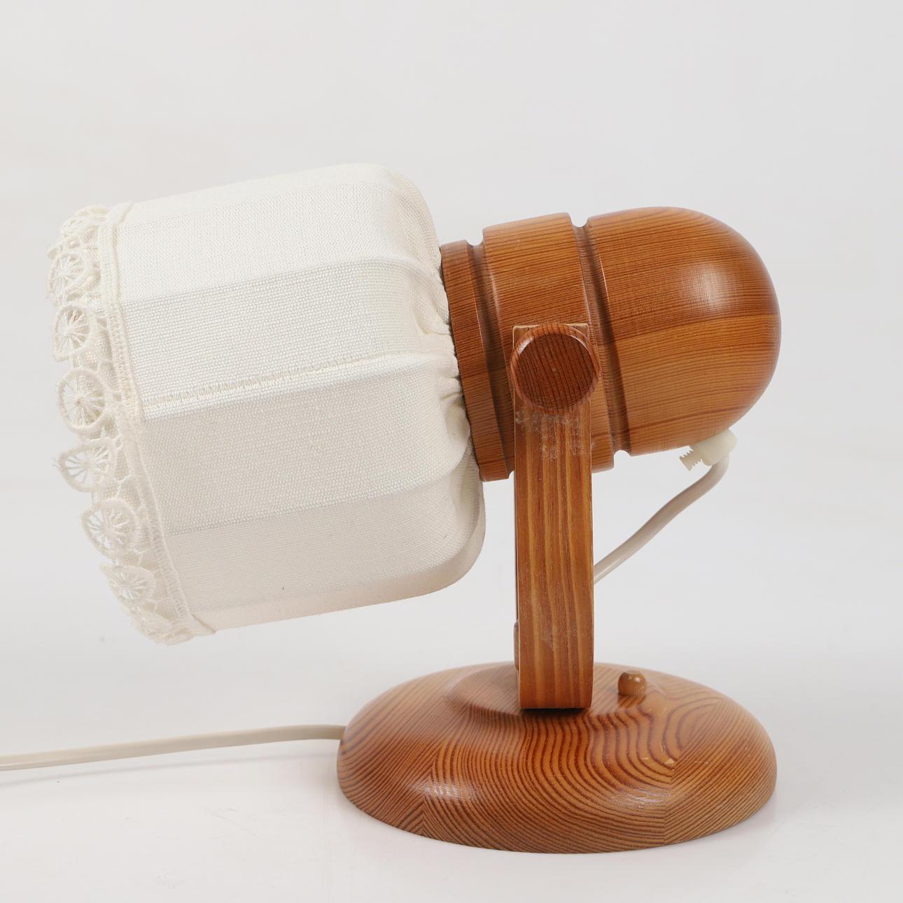 Ein Paar Vintage-Wandlampen von Markslöjd, Schweden, 1970er Jahre. Jede Leuchte hat einen Sockel aus massivem Kiefernholz mit warmer, natürlicher Maserung und einen mit zarter Spitze besetzten Stoffschirm. Das Design verbindet skandinavische