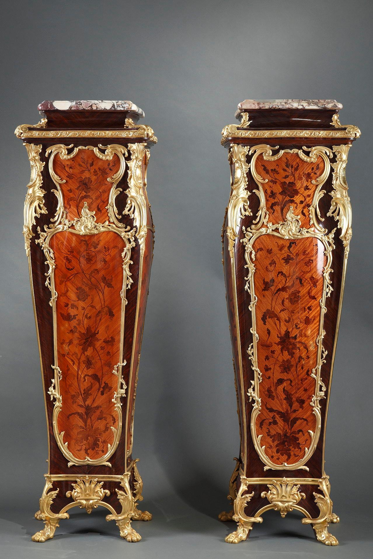 Elégante paire de socles d'inspiration Louis XV attribuée à la Maison Millet. Ils sont décorés sur trois faces d'une belle marqueterie de fleurs stylisées en bois de bout, dans des cartouches aux moulures feuillagées en bronze ciselé et doré. Ils