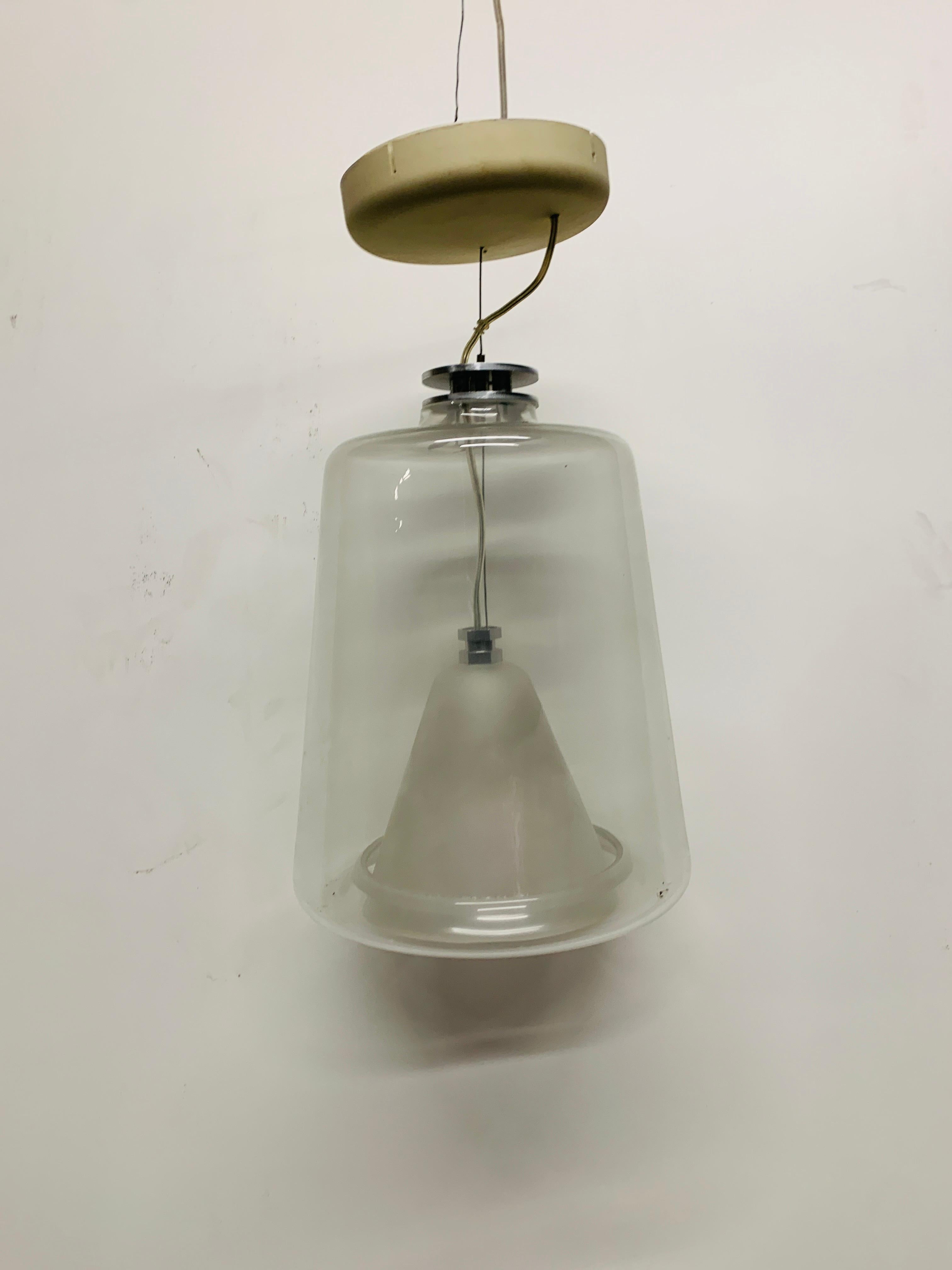 The Oluce Lanterna 477 is an award-winning pendant light. It is from 1998 and was designed by Laudani & Romanelli. The body of the Lanterna 477 is made of transparent and sandblasted glass. This is the larger lamp of this collection. The smaller