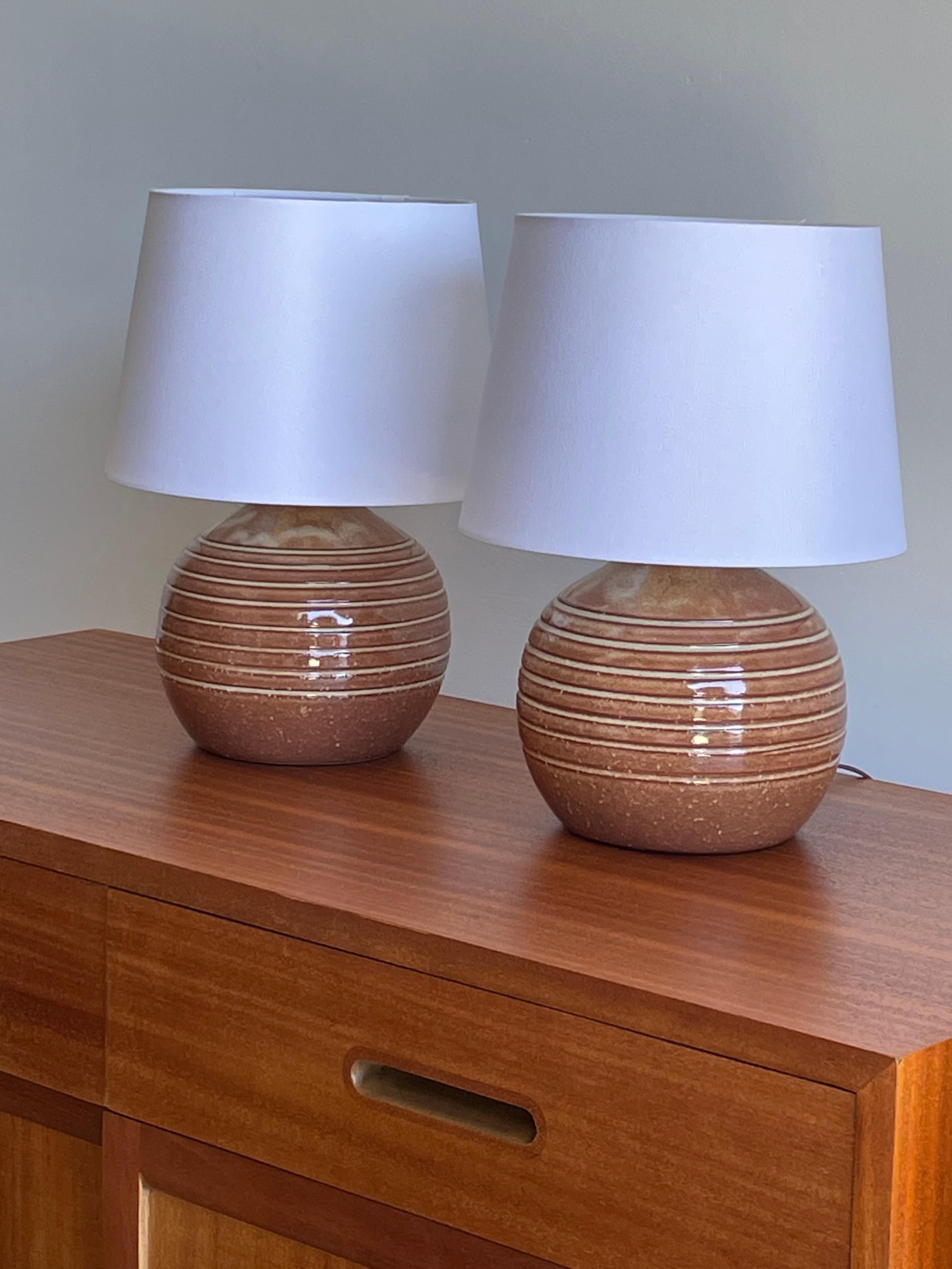 Pair of Martz Table Lamps by famed ceramicist duo Jane and Gordon Martz for Marshall Studios. Lamp bodies are a rose/ blush color with tan incised stripes. 

Measures:
Overall:
13.5” tall
10” wide

 Ceramic only 
7.5” tall
7.5” wide.

Shade is shown